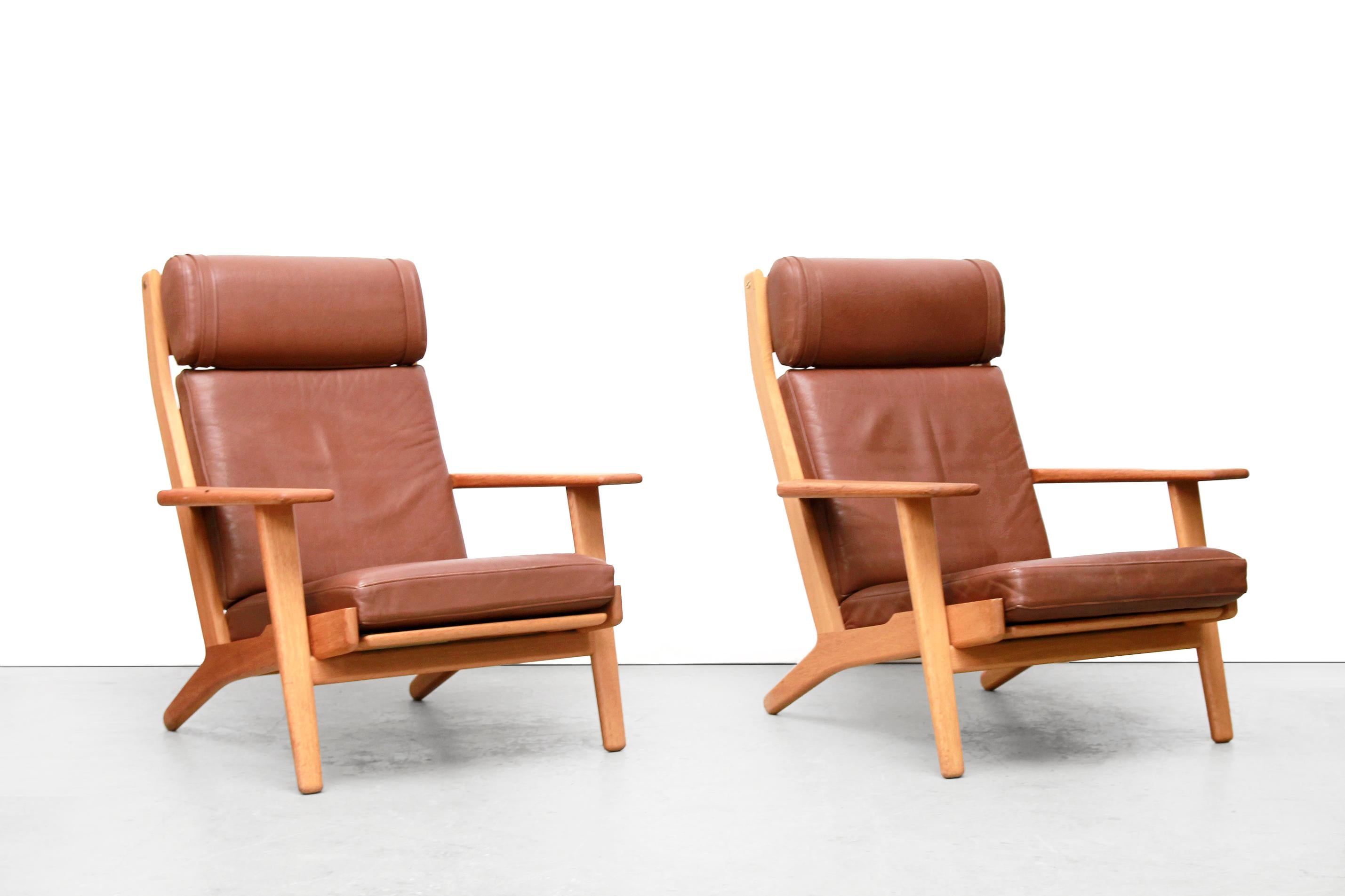 Two armchairs by Danish top designer Hans Wegner. Hans Jørgen Wegner was one of the most inventive of Danish furniture designers. These armchairs are made of solid oak and are originally covered in brown leather. What is very important in Denmark is
