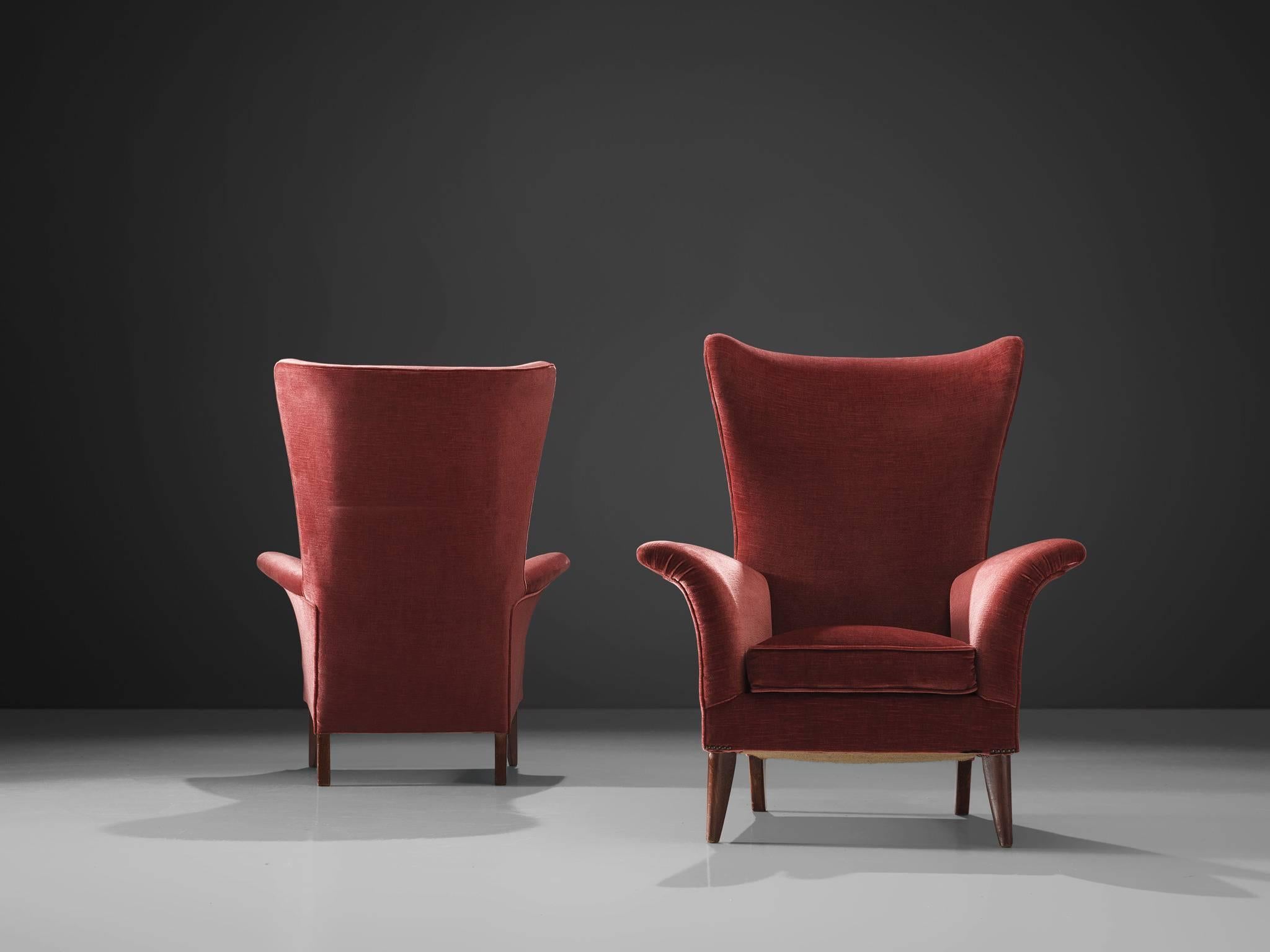 Set of two high wingback chairs, pink velvet and wood, Italy, 1950s. 

Pair of elegant Italian pink to red wingback lounge chairs. Beautiful organic formed seating, with solid wooden legs. The gentle flared armrests and seating give this design a