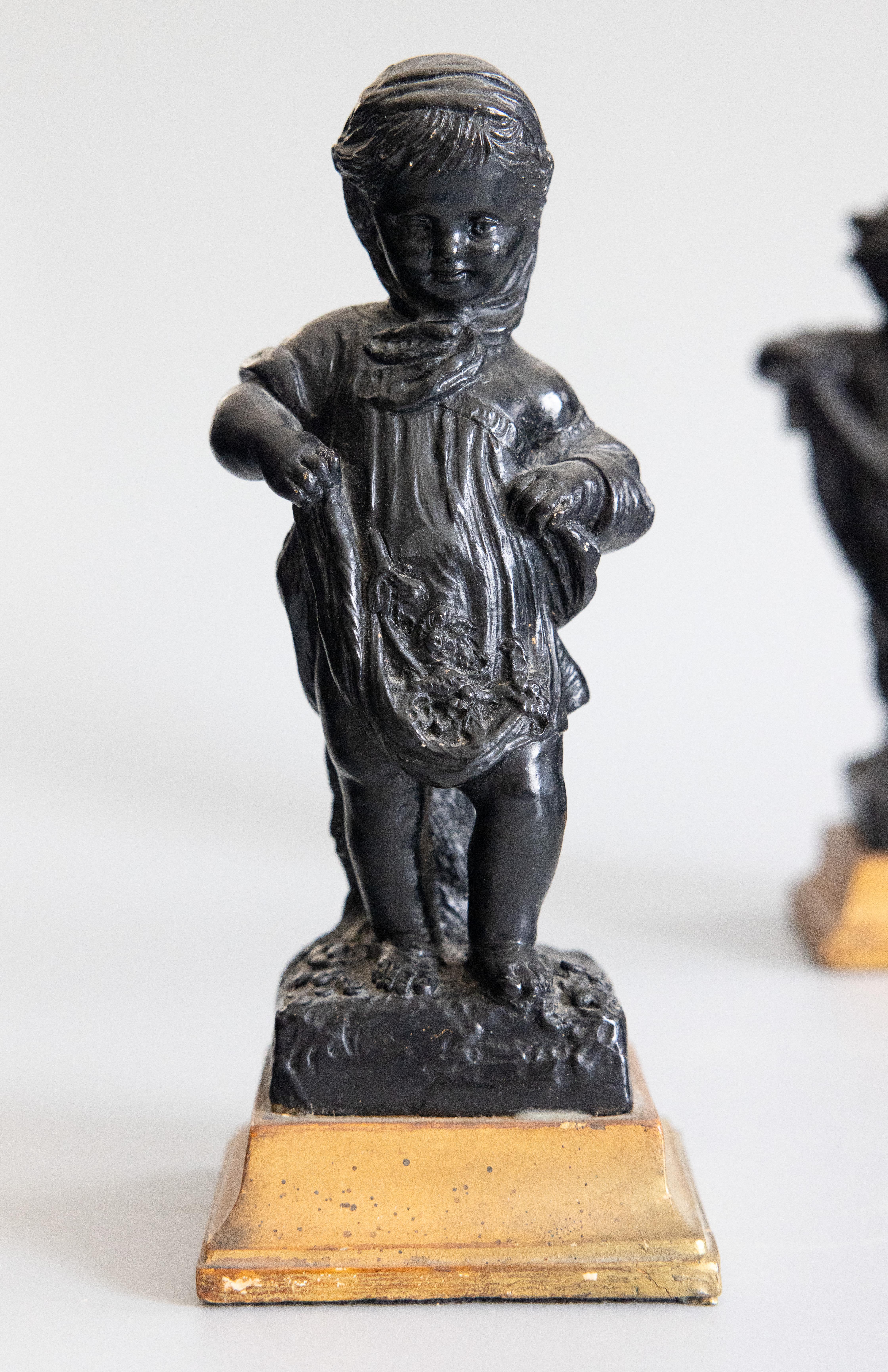 Un affascinante set di due putti o putti italiani di Borghese, circa 1930. Sulla base di uno di essi è rimasta una parziale etichetta del produttore. Questi dolci putti sono ebanizzati su zoccoli dorati, raffigurati con espressioni giocose mentre