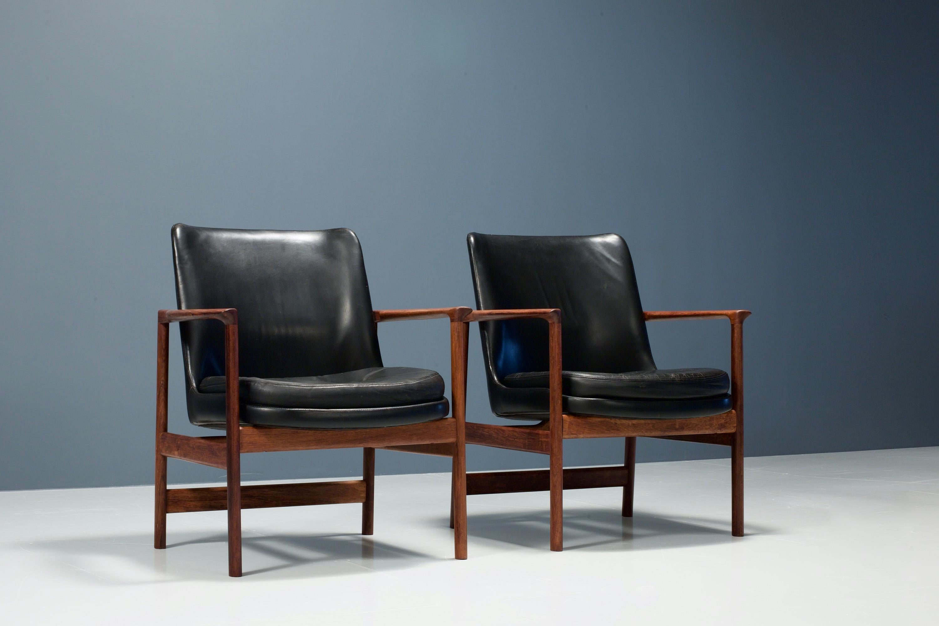 Set of two black armchairs designed by Ib Kofod-Larsen with leather and teak from Denmark, 1960s. These chairs are manufactured by Froscher KG. The chairs are in good condition and have been fully restored using the original leather of course.
Both