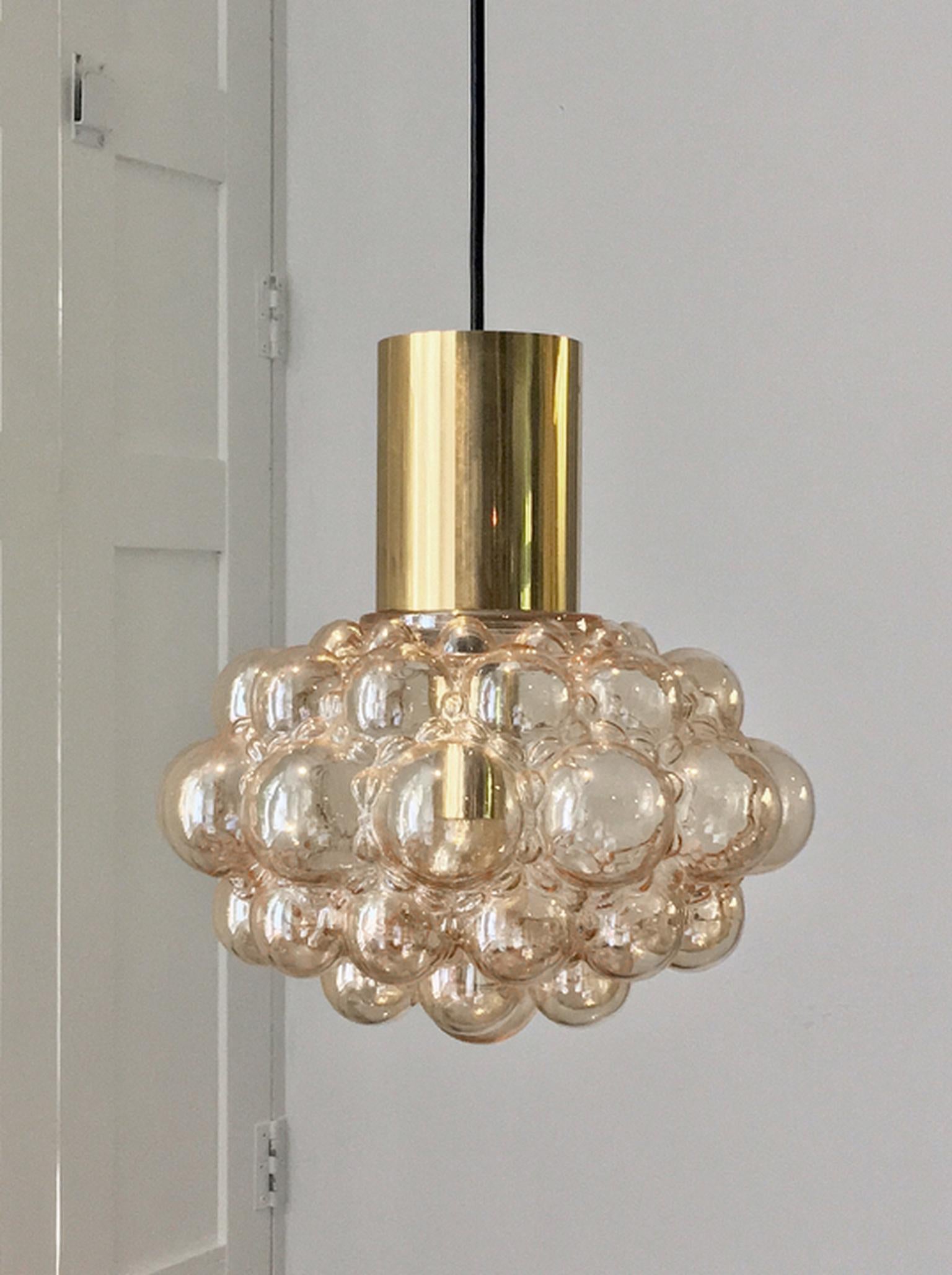 Set of two midcentury glass chandeliers or pendant lights by Finnish designer Helena Tynell - wife of designer Paavo Tynell - for Glashu¨tte Limburg of Germany. 

These attractive fixtures comprise a glass shade of pale amber, with brass tubes