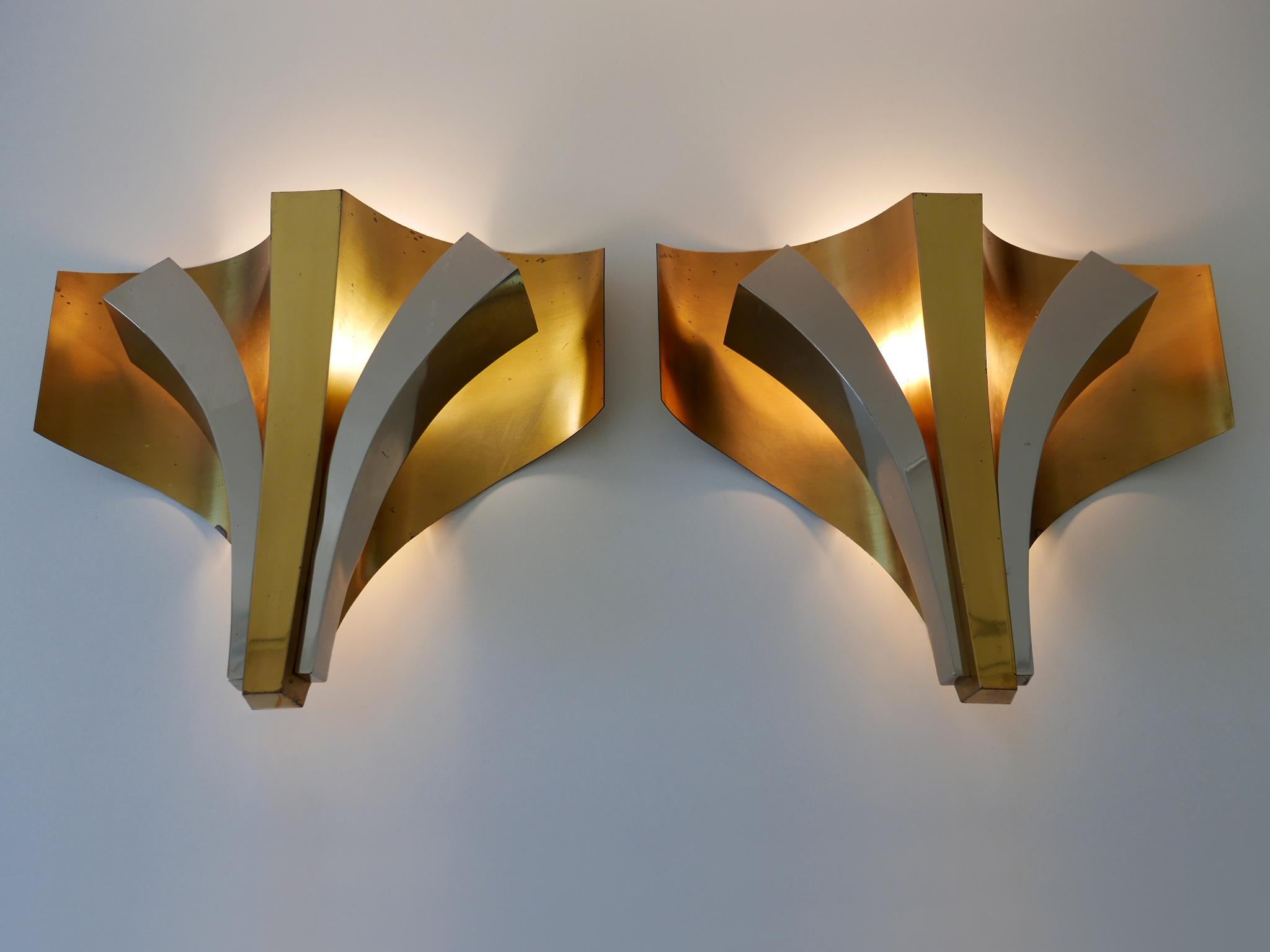 Set of two elegant Mid-Century Modern three-flamed brass sconces. Designed and manufactured by Maison Baguès Paris, France, 1960s. Signed reverse: Baguès Paris.

Executed in brass; partly nickel-plated, each sconce comes with 1 x E27 / E26 and 2 x