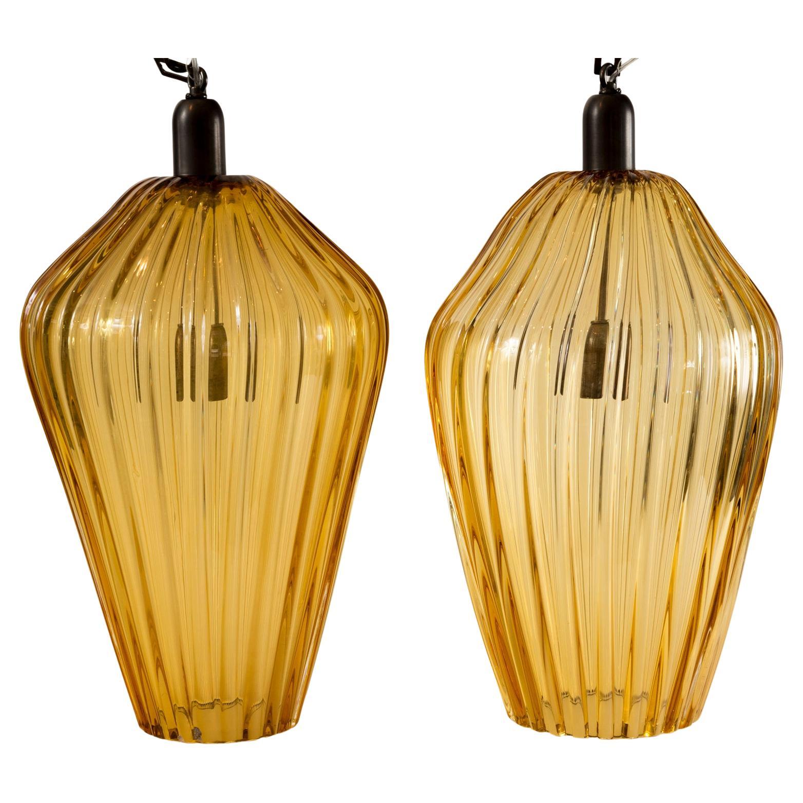 I pendenti in ambra soffiata a coste spesse con lampade in ottone rifinite in bronzo e ciascuna elettrificata con una presa in porcellana E26 per un alto wattaggio, con certificazione UL.

Il suo colore ha più toni tabacco che arancioni e si legge