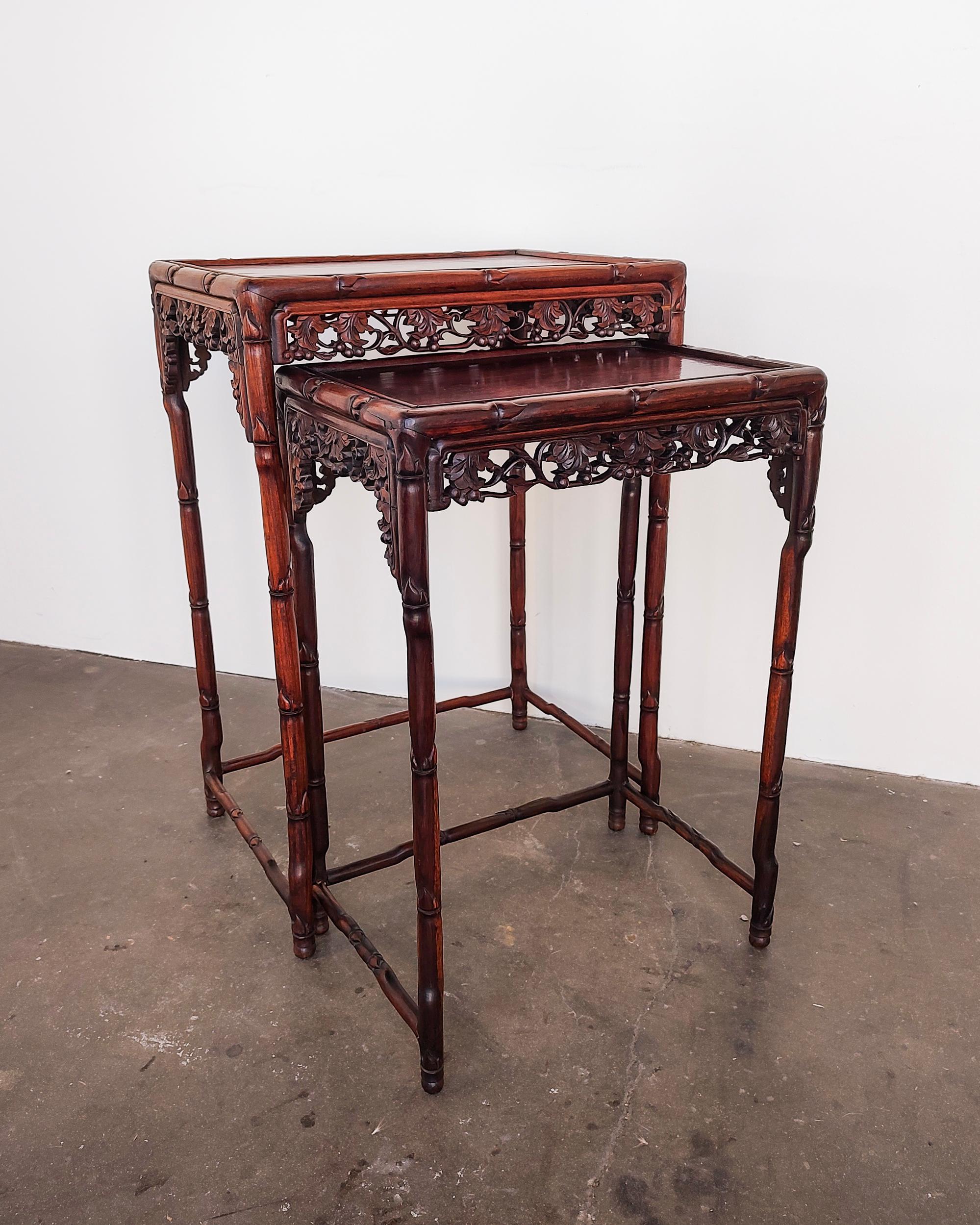 Pair of Chinese rosewood nesting tables circa late 19th century. Intricate bamboo and floral carvings and delicate solid rosewood legs. Overall great original condition, some light wear present, area of discoloration on the top of the larger