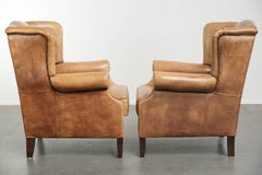 Lot de deux fauteuils à oreilles en cuir de vachette clair, au style anglais intemporel