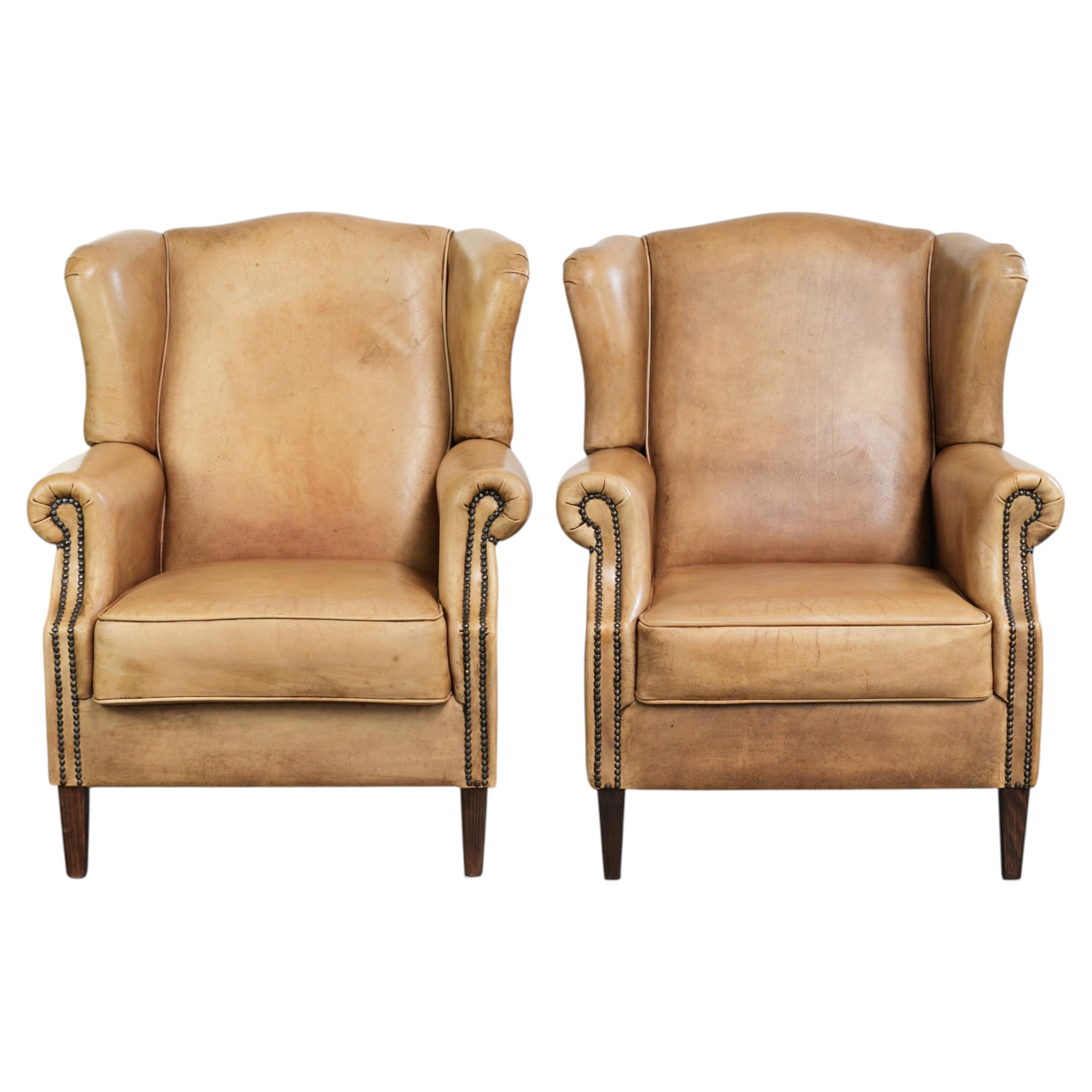 Set of two light cowhide wingback armchairs with a timeless English look For Sale