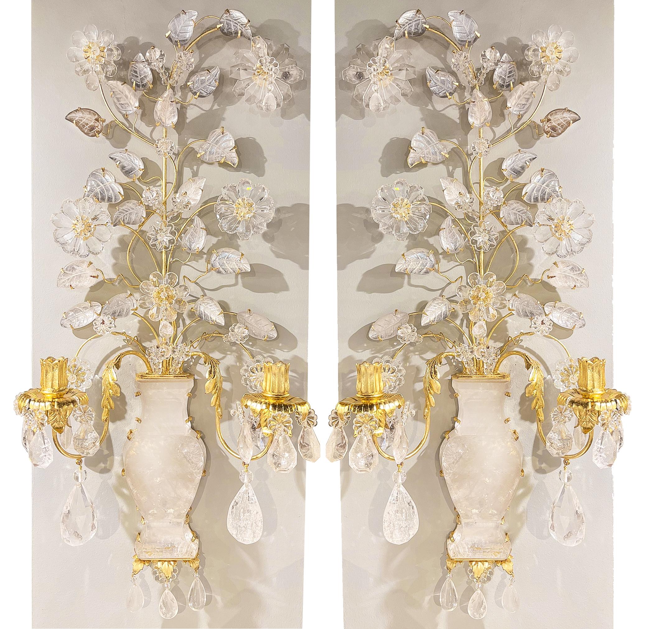 Intricately handcut and carved rock crystal sconces in the form of a vase of flowers. The main anchor of the sconce is a central bellied vase with gilt metal branches bursting from the lip. Decorative floral and leaf accents carved in rock crystal