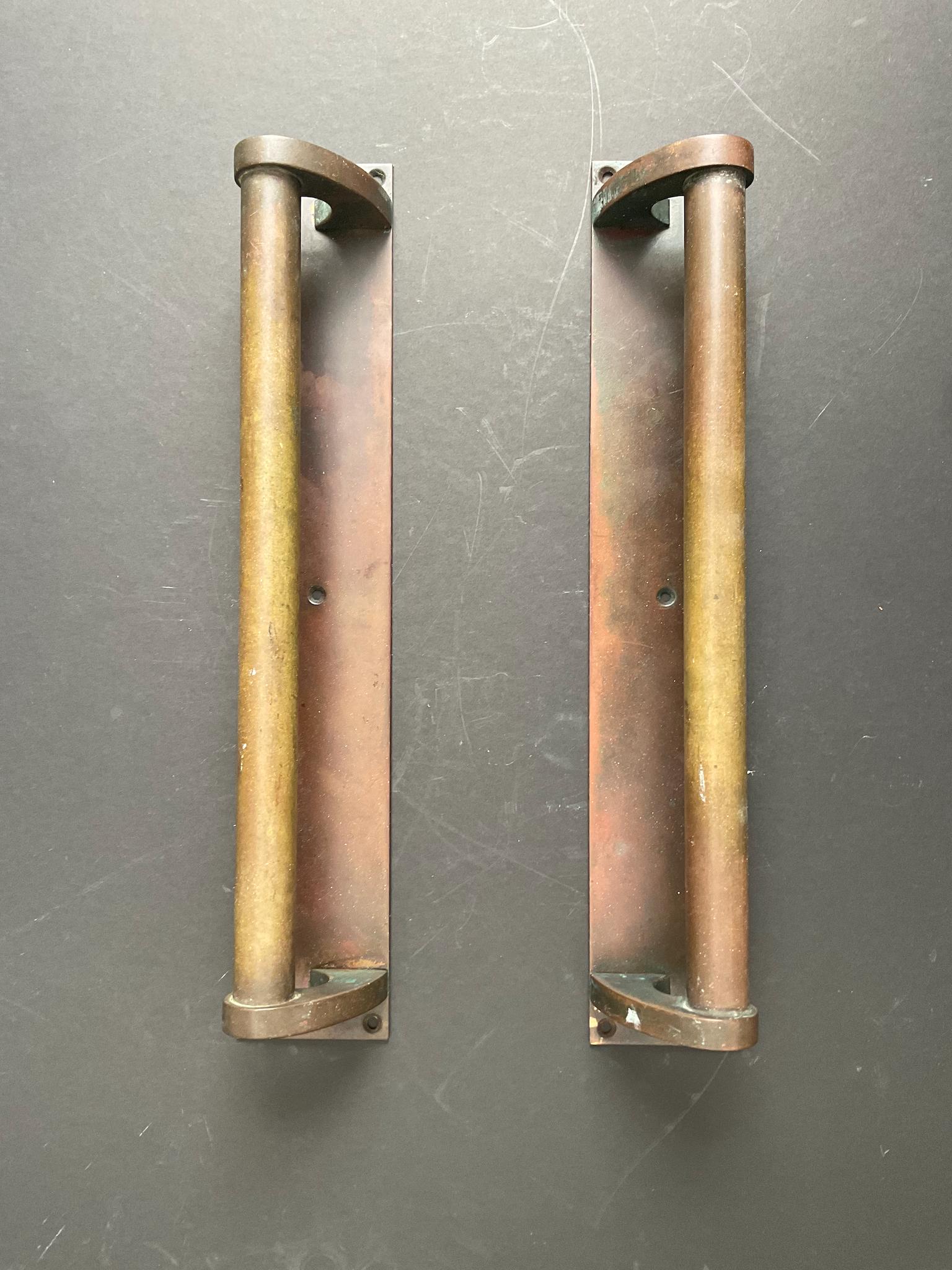 A pair of bronze door handles, each with a long rectangular mounting plate. First half twentieth century, found in England.

The handles are a very simple design, made from bronze (or other copper-based metal) with a heavy aged patina - brown, red