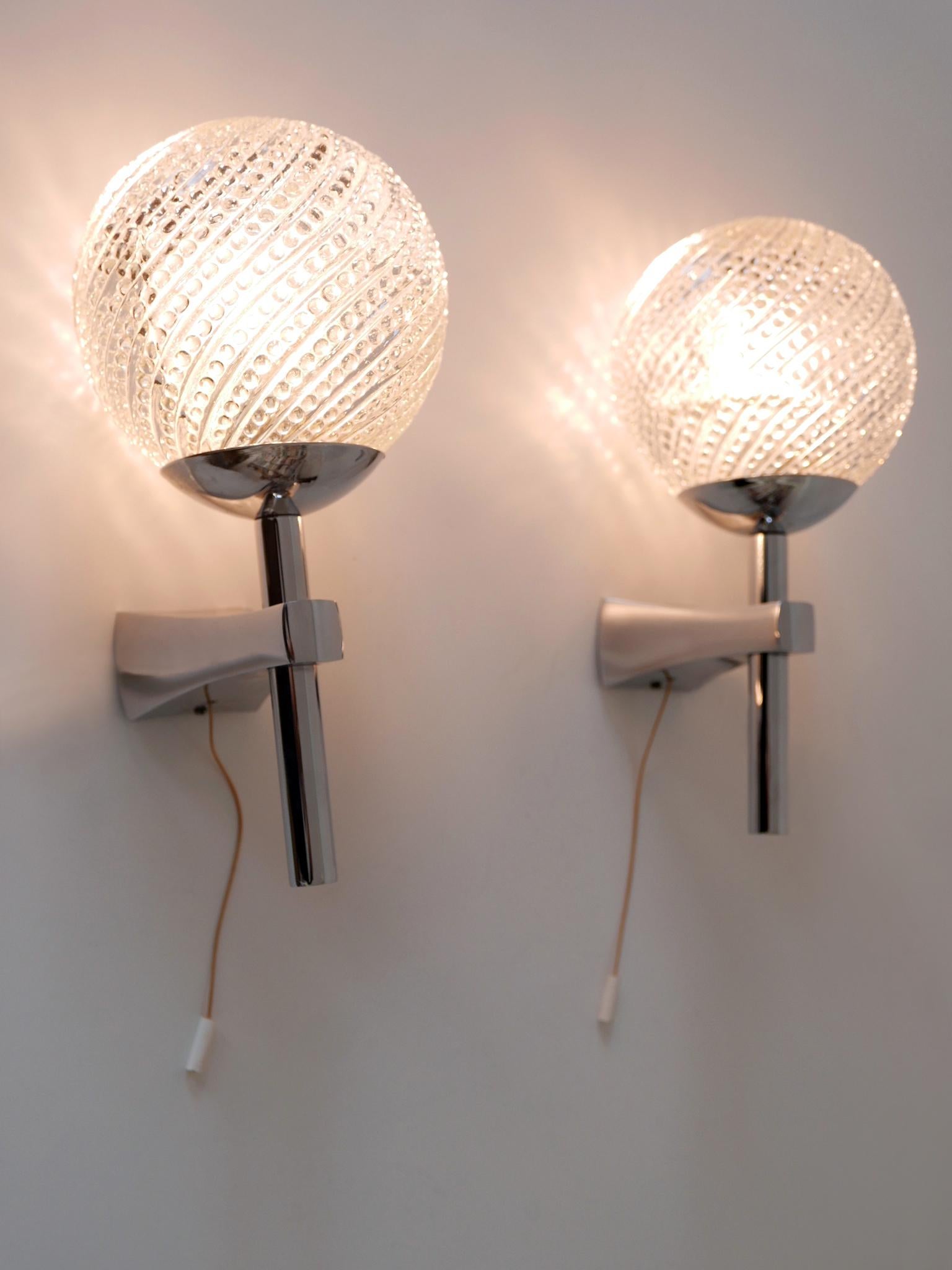 Set of two elegant Mid-Century Modern sconces or wall lights. Designed & manufactured in Germany, 1970s.

Executed in textured glass and chrome-plated brass, each sconce is executed with 1 x E14 / E12 Edison screw fit bulb socket, is wired and in