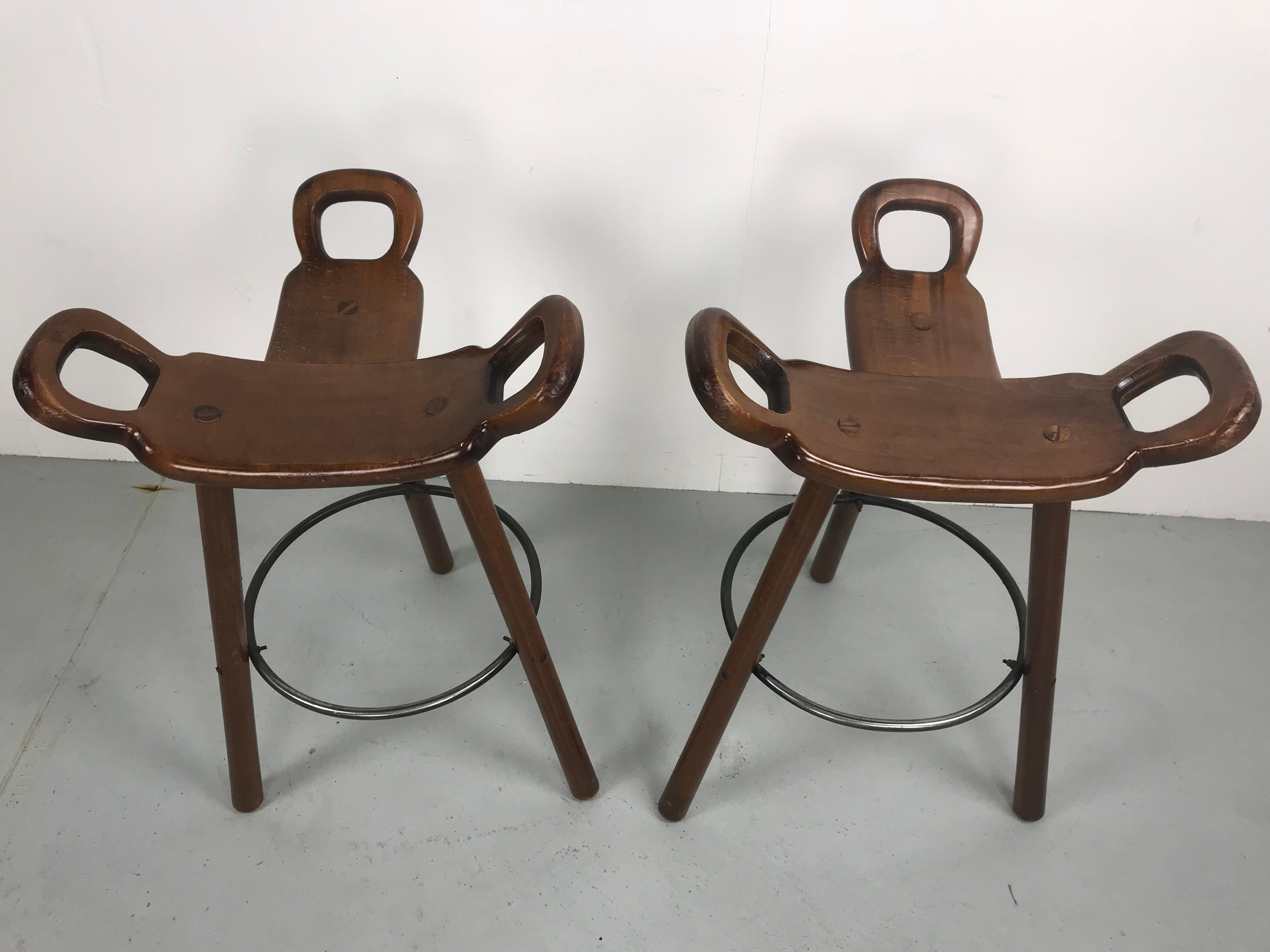 Set of two 'Brutalist' or 'Marbella' bar stools, in brown oakwood and metal, Spain, 1970s. 

Set of two Brutalist bar stools in brown stained colour. The eye-catching part is the seating. A curved T-shape with three handles. The handles are not