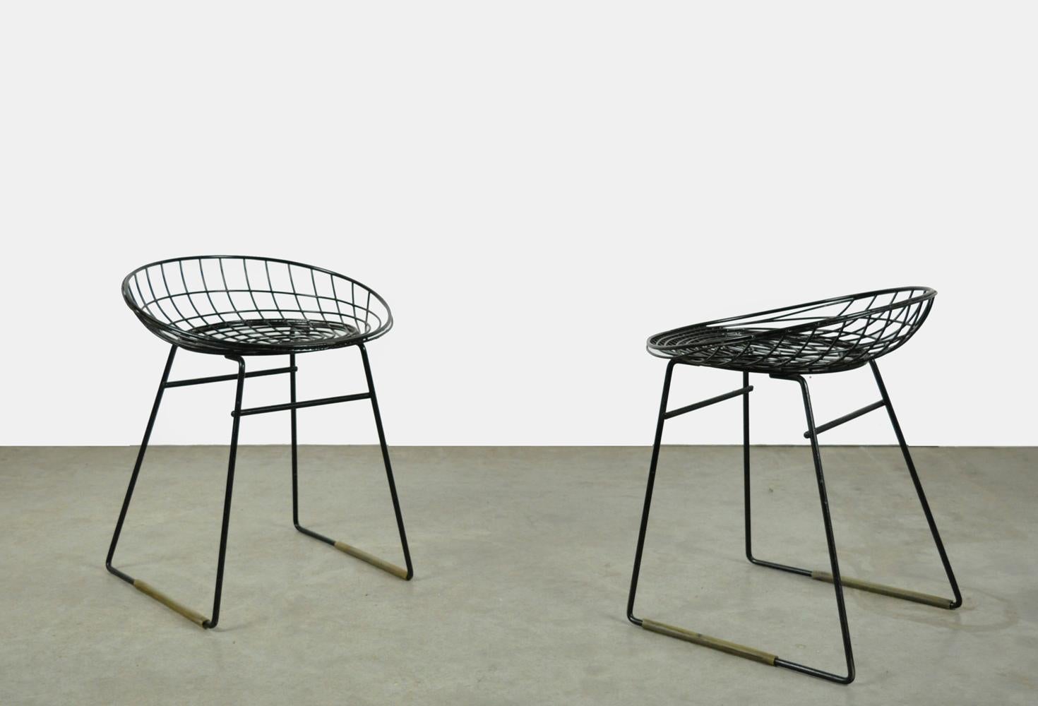 Ensemble de deux tabourets en fil d'acier, modèle KM05, conçus par Cees Braakman et Adriaan Dekker pour Pastoe, années 1950. Les fils métalliques sont recouverts d'une couche de plastique noir. Le tabouret métallique a été conçu en collaboration