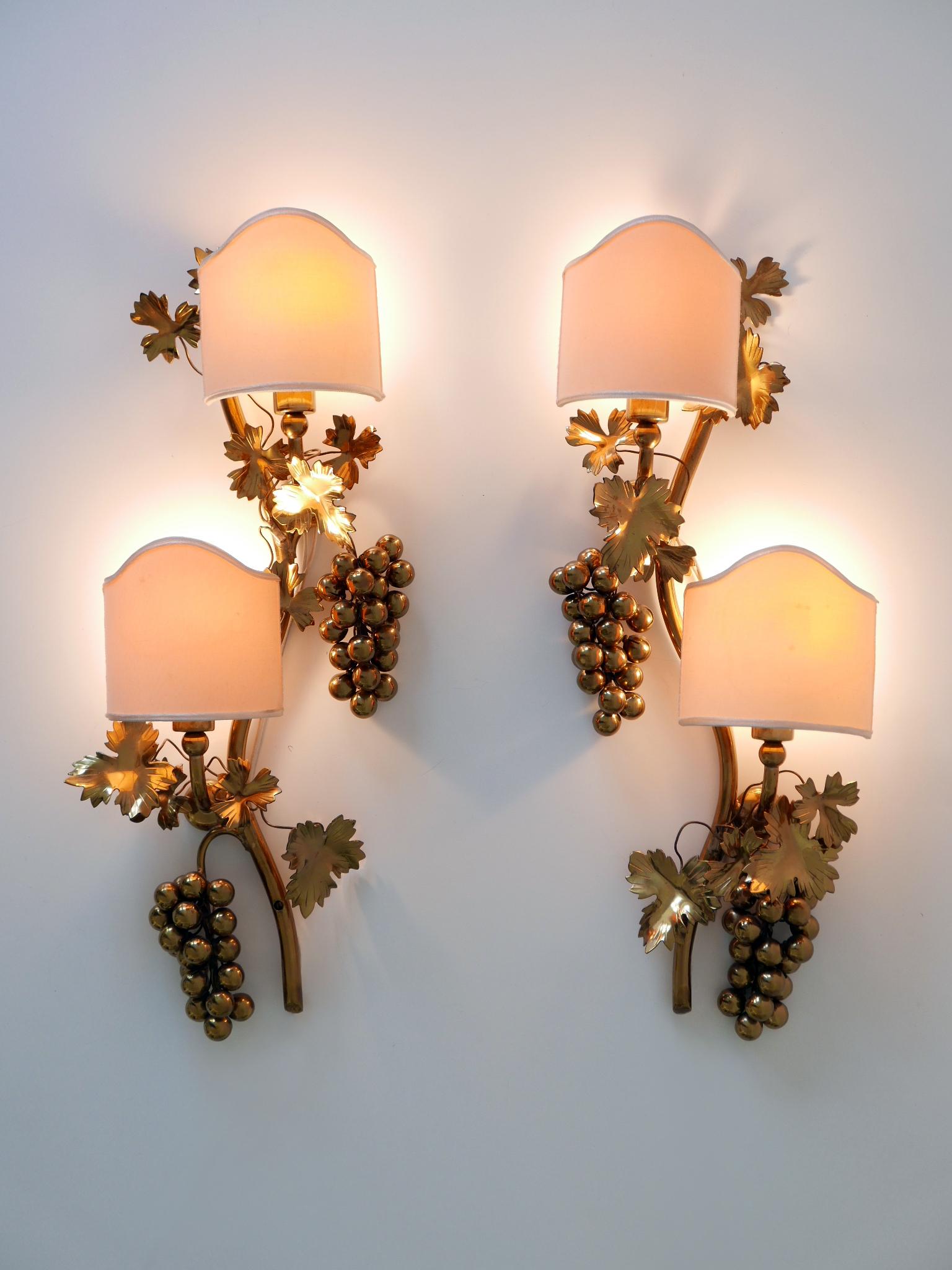 Set of two exceptional, elegant and highly decorative Mid-Century Modern brass grape vine leaves sconces or wall fixtures. Designed & manufactured in Germany, 1970s.

Executed in brass and fabric, each fixture is executed with 2 x E14 / E12 Edison
