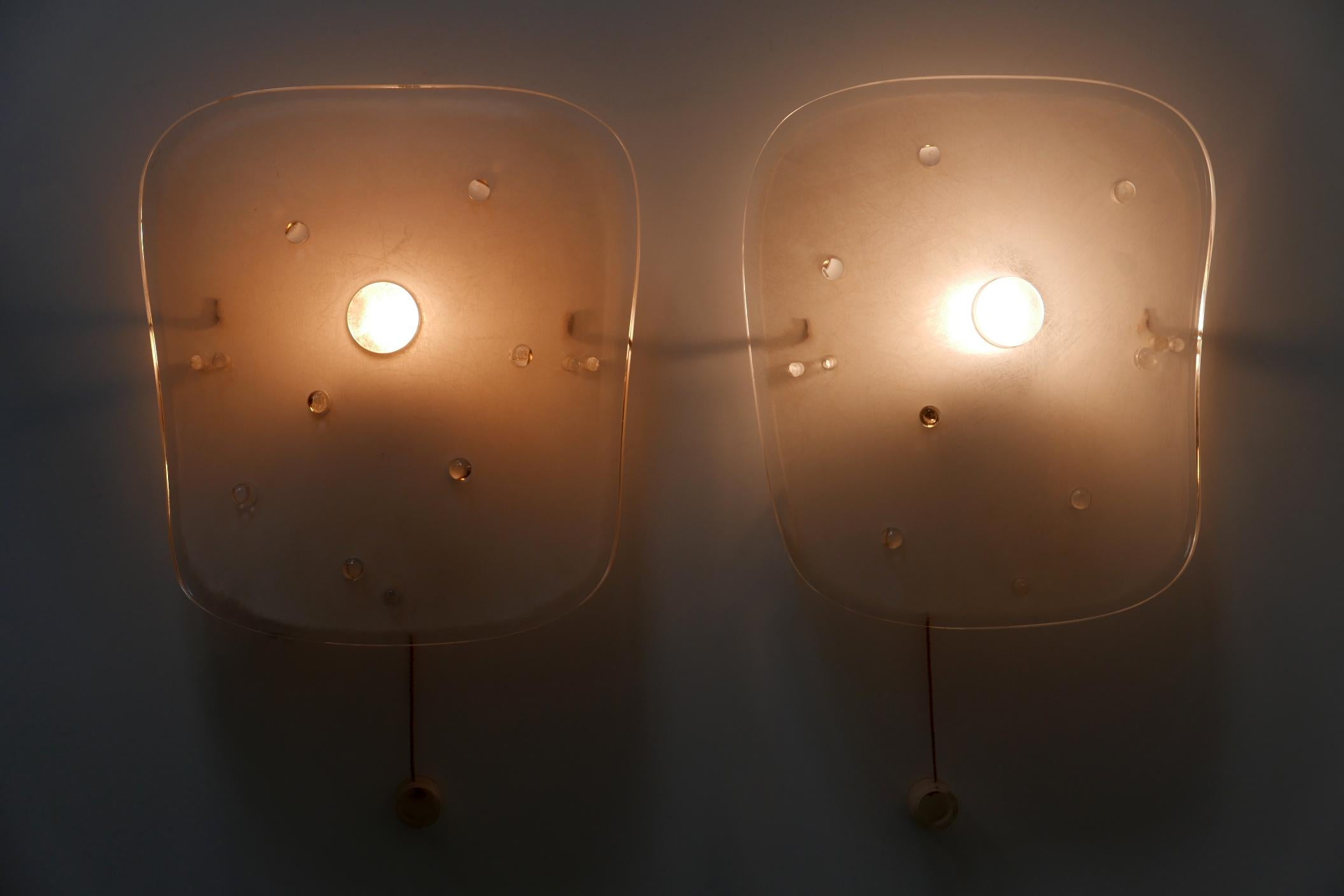 Set of two rare and highly decorative Mid-Century Modern Lucite wall lamps or sconces. Manufactured probably by Rupert Nikoll, 1960s, Austria.

The lamps are executed in textured plexiglass with brass base. Each lamp needs 1 x E27 / E26 Edison
