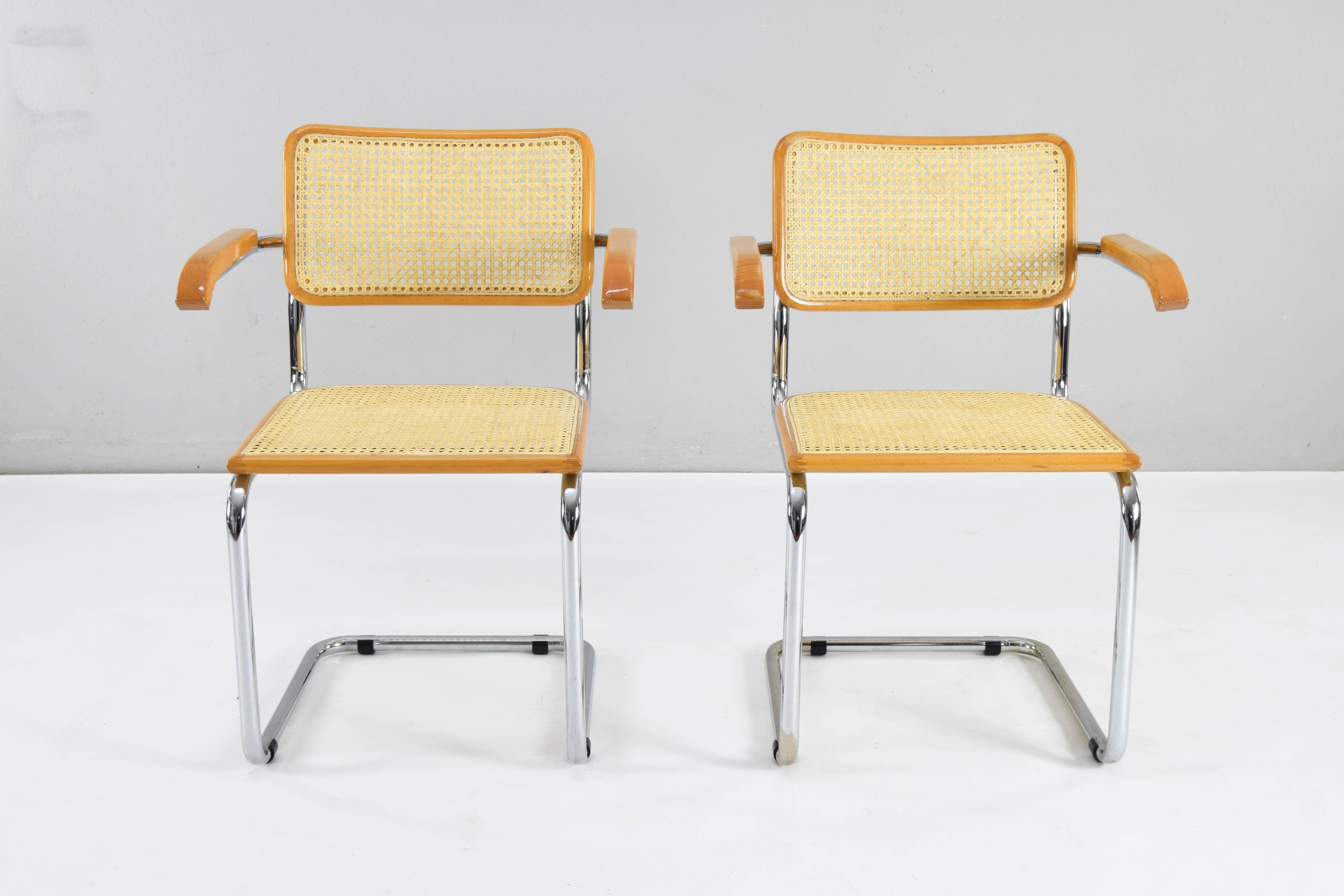 Ensemble de deux chaises Cesca modèle B64, avec accoudoirs. Structure en tube d'acier chromé, bois de hêtre et grille viennoise naturelle. 
Structure tubulaire chromée avec des zones d'usure au bas de certaines d'entre elles mais en bon état.
Les