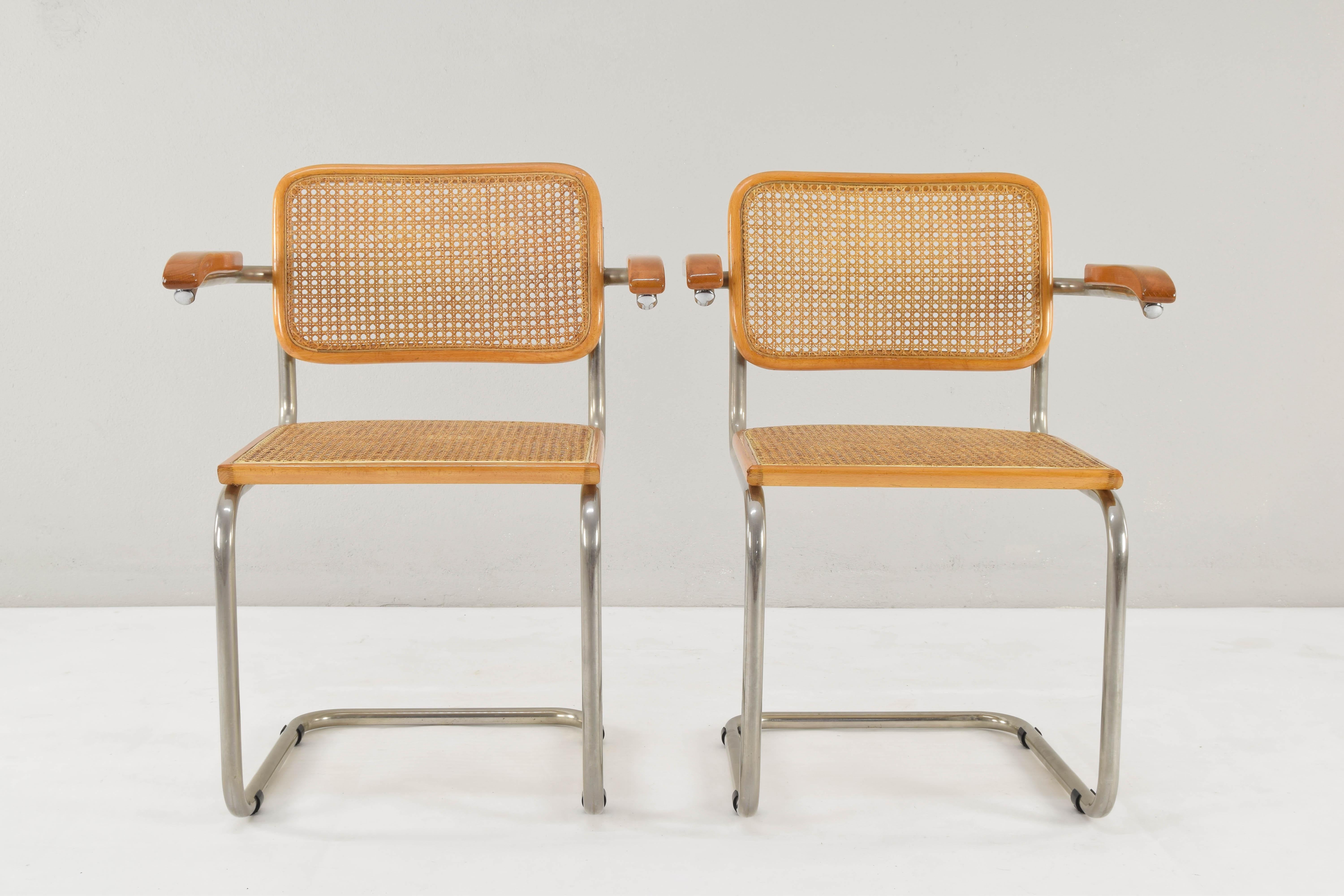 Set of two Cesca chairs model B64, with armrests. Tubular steel chromed structure, beechwood and Viennese natural grid. 
Chrome tubular structure with wear areas at the bottom of some of them but in good condition.
Grids of the two seats have been