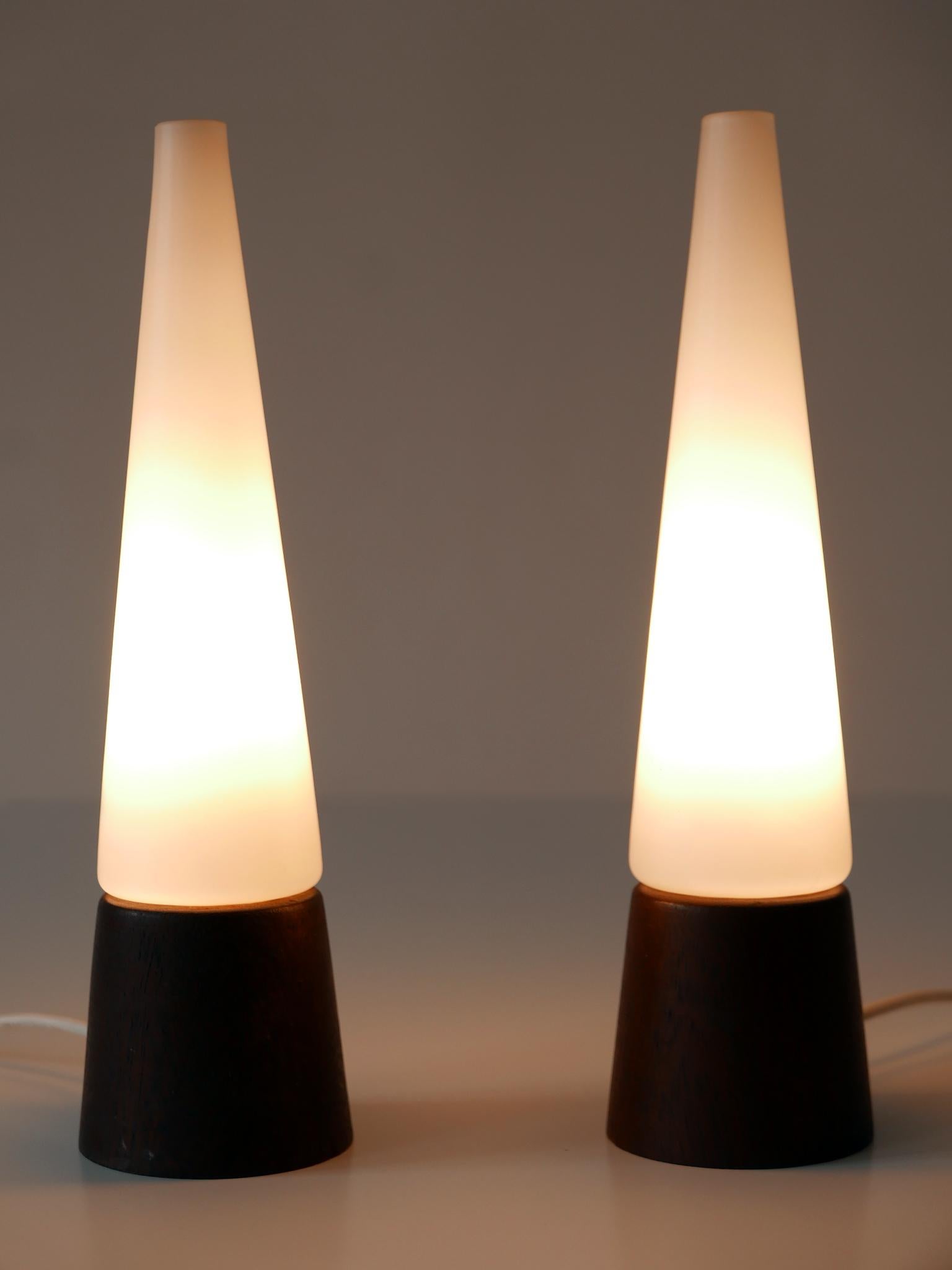 Set of two elegant and highly decorative Mid-Century Modern table lamps. Designed and manufactured in Scandinavia, 1960s.

Executed in opaline glass and teak wood, each lamp comes with 1 x E14 / E12 Edison screw fit bulb socket, is wired, in