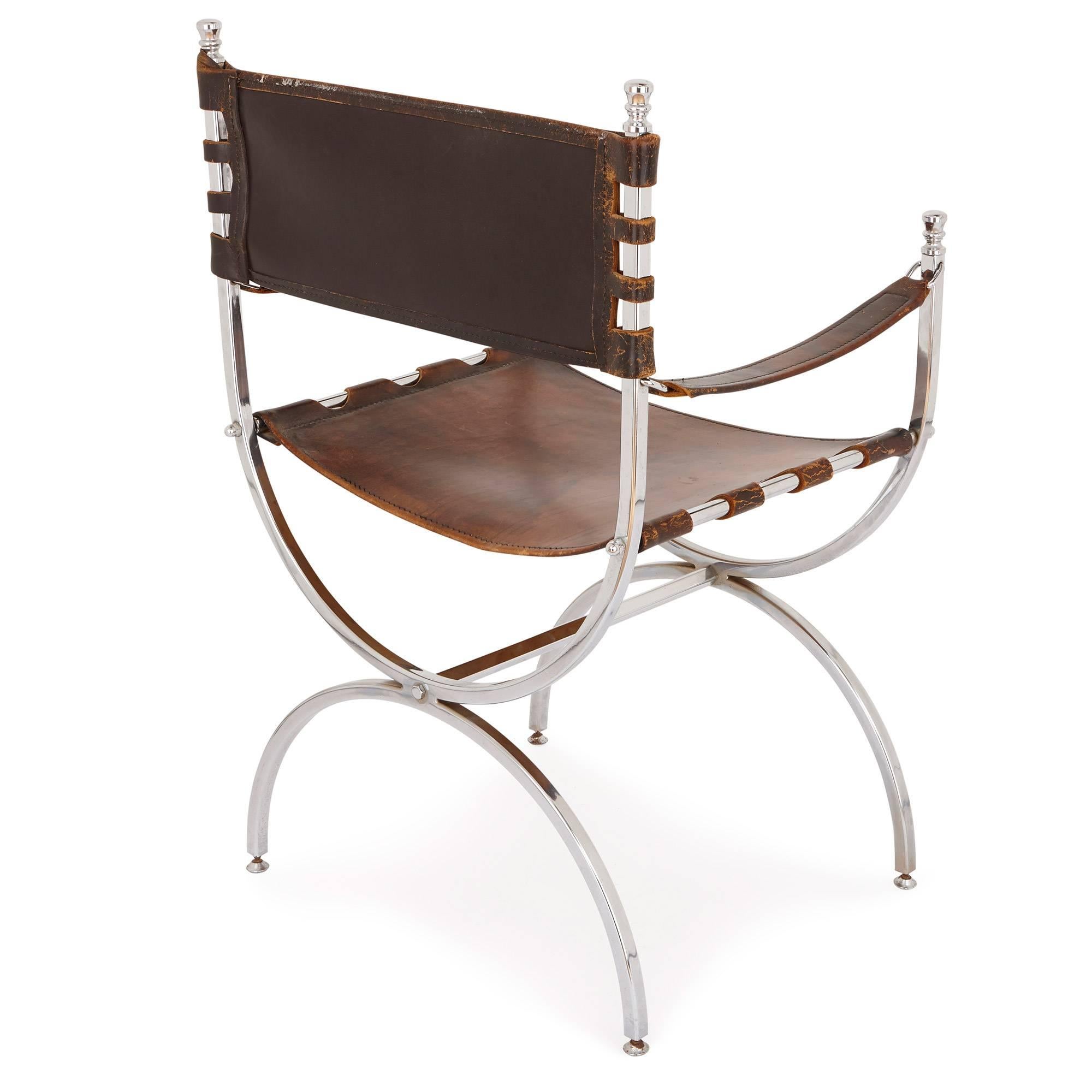 These two chairs are designed and executed with the sleek, minimal design of French modernism. They are crafted with chic, curving silvered metal which takes an X-form. Between the silvered frame are stretched brown leather sheets, forming supple
