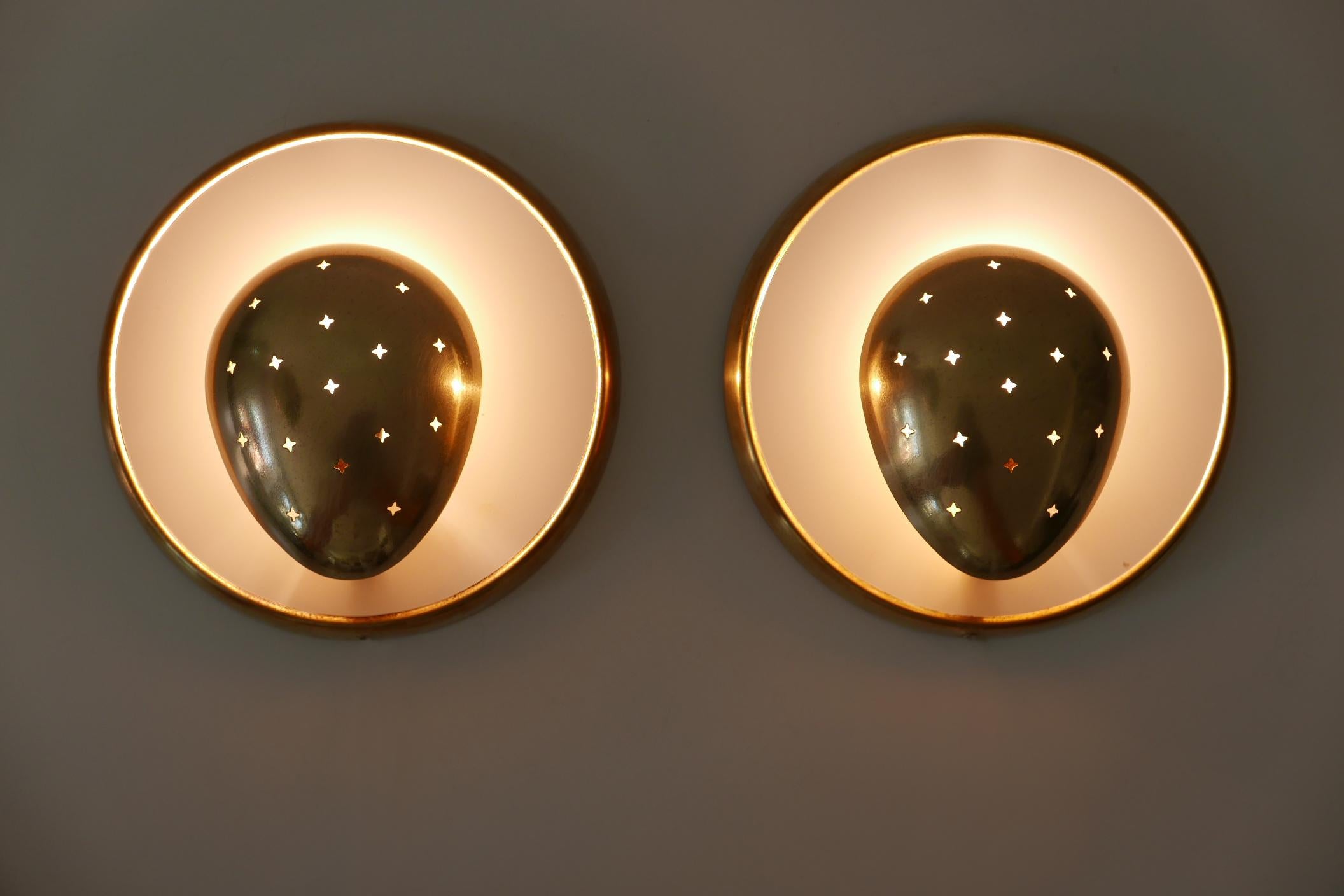 Set of two extremely rare and beautiful Mid-Century Modern brass wall lamps or sconces. Designed and manufactured probably in France, 1950s.

The lamps are executed in partly white enameled and perforated brass and each lamp needs 1 x E14 Edison