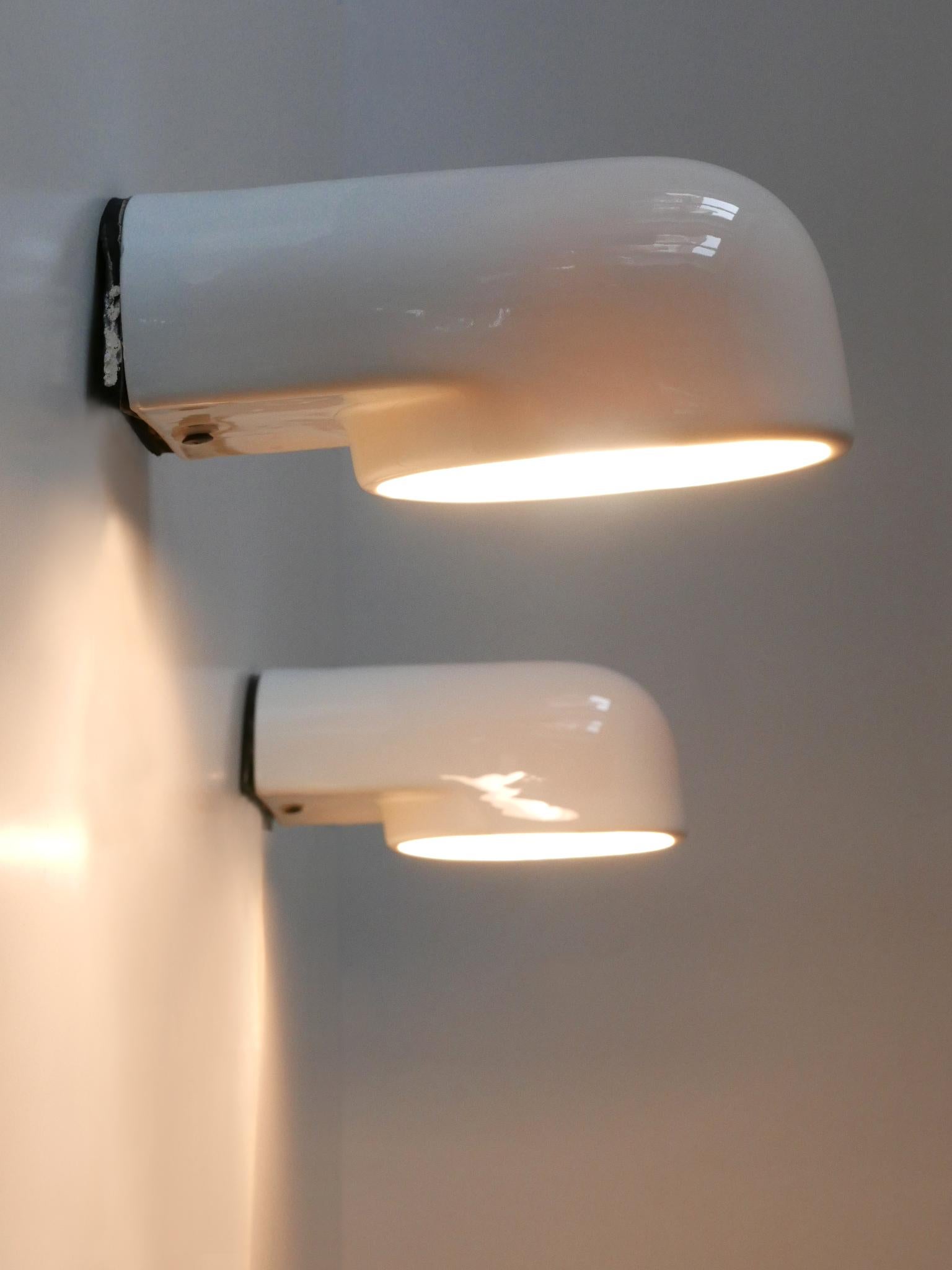Set of two rare and elegant mid-century modern up & down lighter sconces. Model 'Pafo'. Manufactured by Artemide, Italy, 1970s.

Executed in glazed white ceramic and metal, each lamp needs 1 x E27 / E26 Edison screw fit bulb, is wired, in working