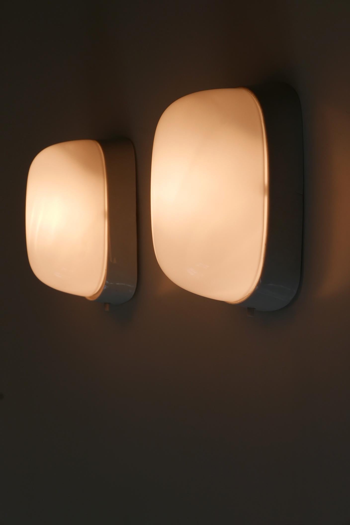 Set of two rare and elegant Mid-Century Modern ceramic sconces or wall fixtures. Designed probably by Wilhelm Wagenfeld für Lindner, Germany, 1950s. 

Executed in white ceramic and opaline glass, each fixture comes with 1 x E27 / E26 Edison screw