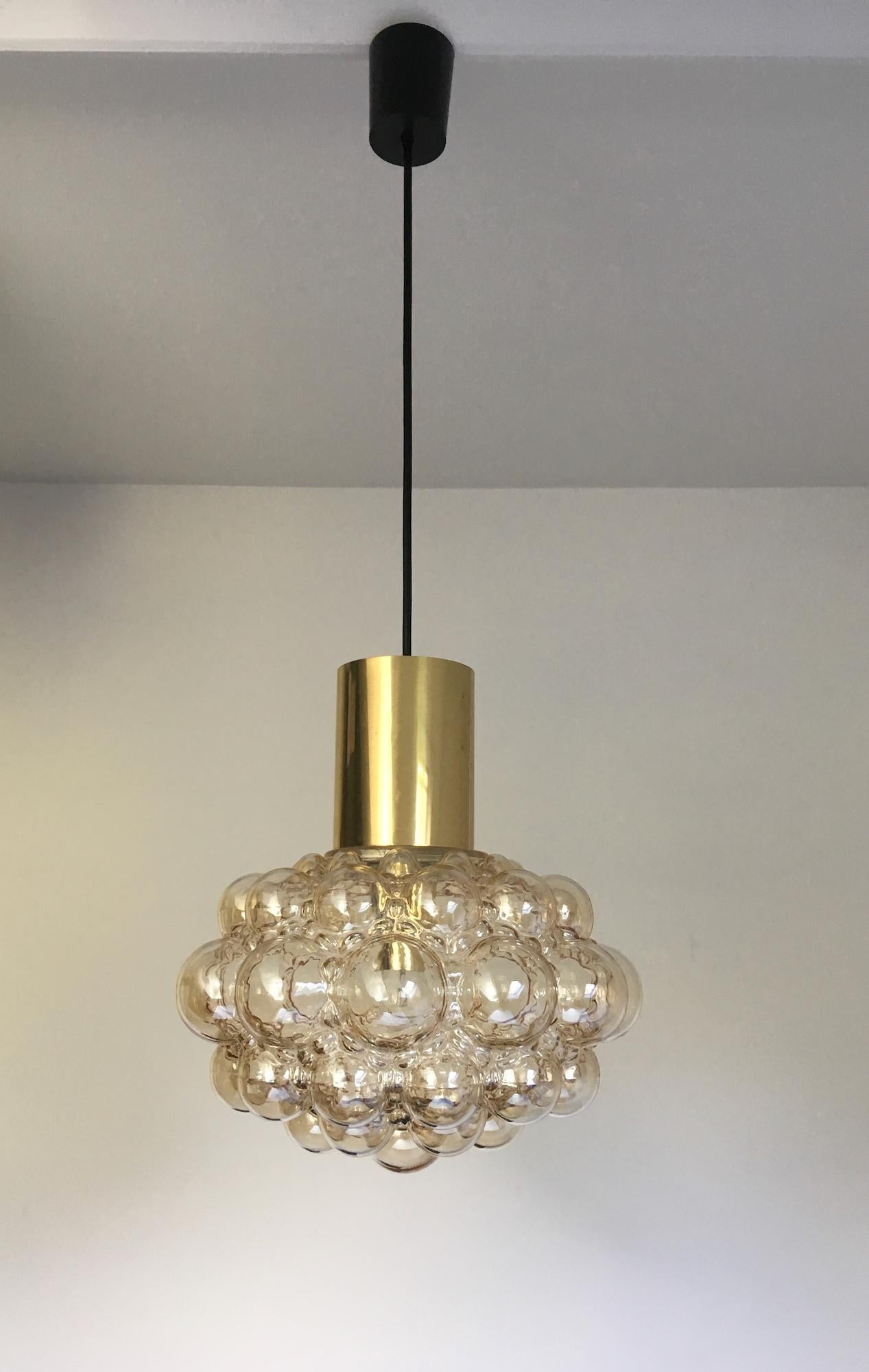 Set of two midcentury glass pendant bubble lights by Finnish designer Helena Tynell for Glashütte Limburg of Germany. 

These attractive fixtures consist of a glass shade of pale amber, topped with a brass tube. The brass simply rests on the