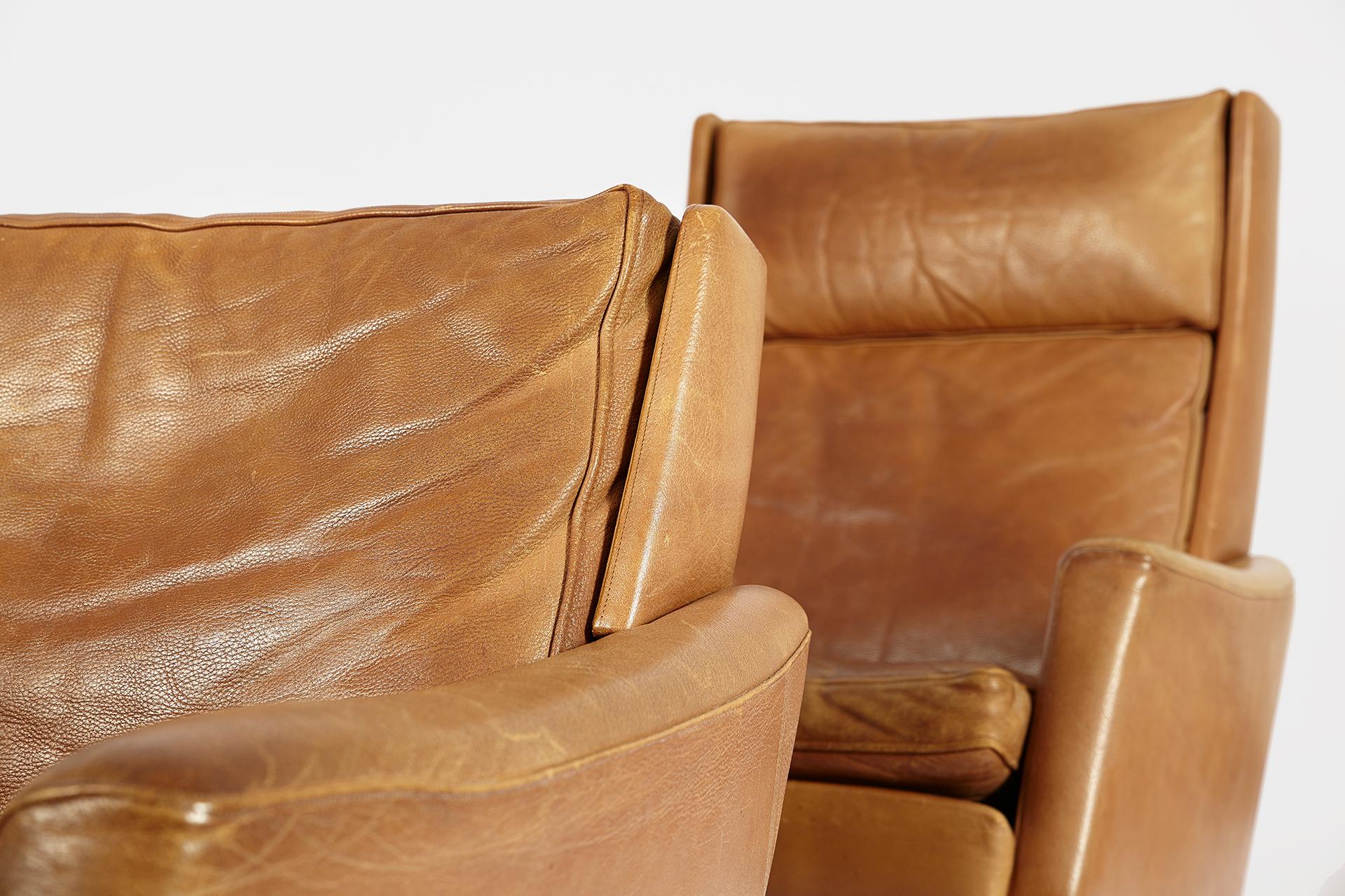 Set of two matching Danish midcentury lounge chairs of caramell-brown leather featuring strong elegant lines and high comfort. The swivel chairs have high quality grained leather upholstery with beautiful patina.