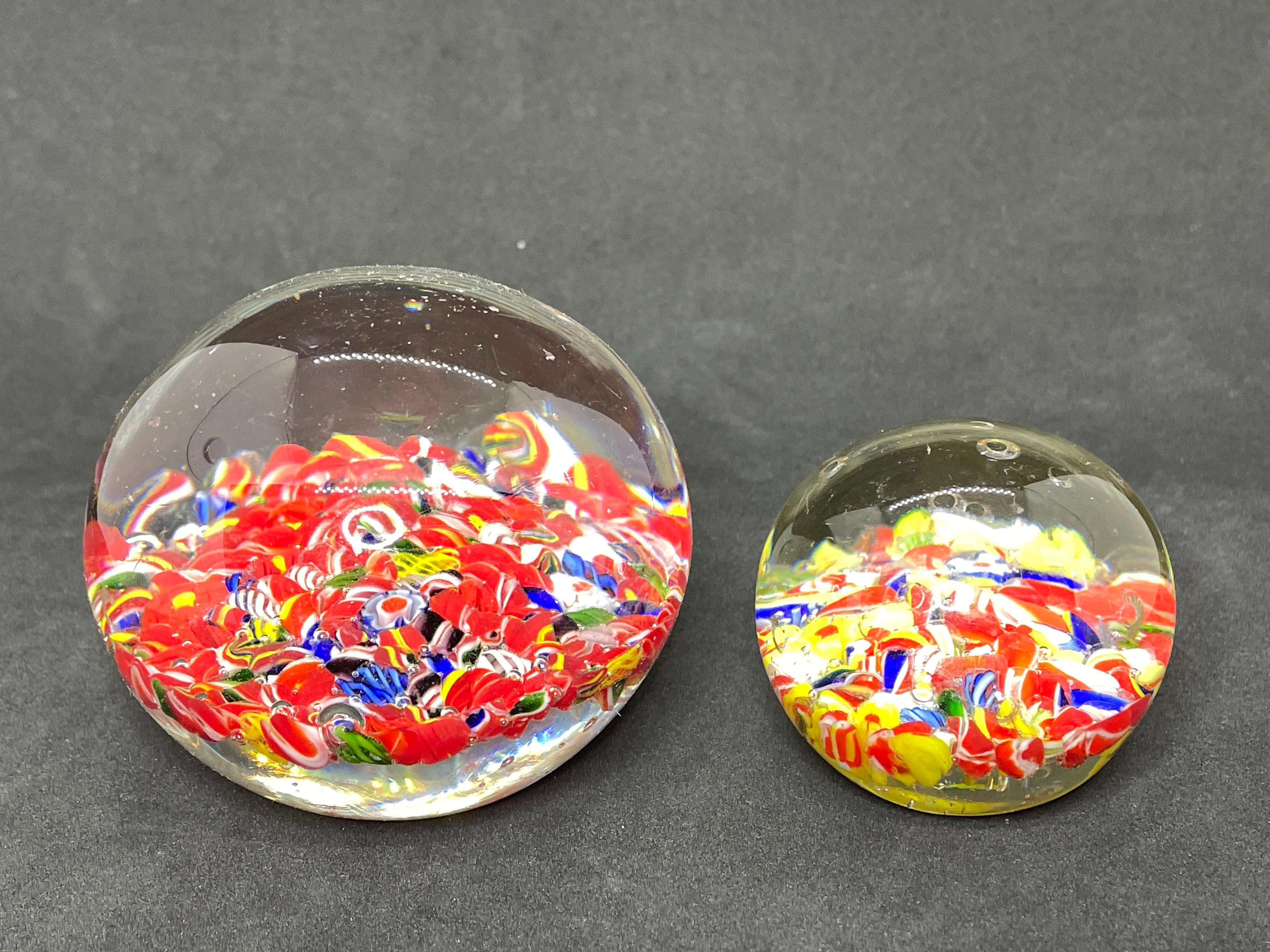 A set of two beautiful Murano hand blown Italian art glass paper weight. Showing some flowers. Colors are a blue, white, red and clear. A beautiful nice addition to your desktop or as a decorative piece in every room.