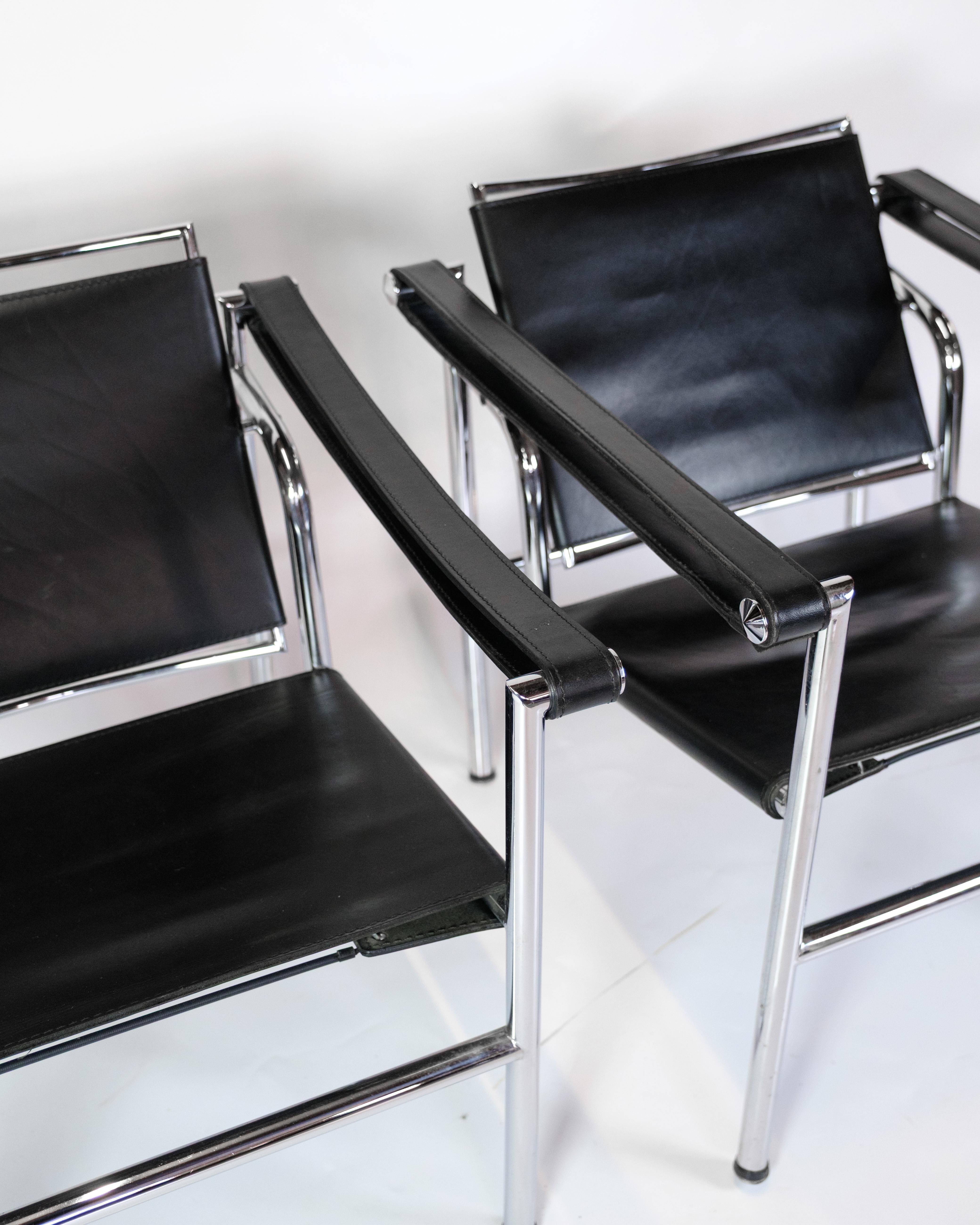 Una coppia di poltrone classiche in pelle nera pieno fiore con struttura cromata. Il modello LC1 è stato progettato nel 1928 da Le Corbusier. Lo schienale della sedia è regolabile. Sono in ottime condizioni sia per quanto riguarda le cromature che