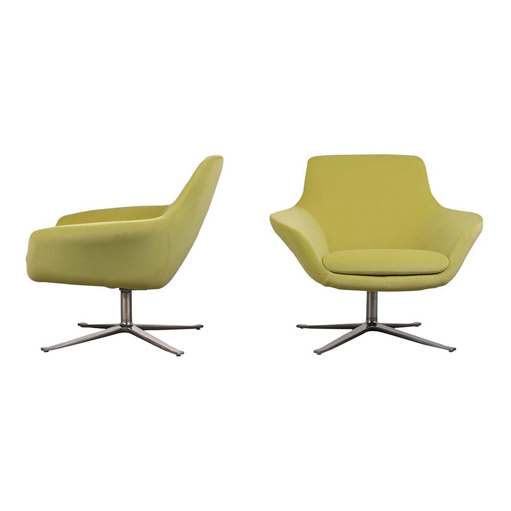 This restored set of 1980s lounge chairs are upholstered in light green velvet fabric and finished topstitch details. The chrome X-base allows the chairs to rotate with ease. This pair of swivel lounge chairs are sturdy, sleek, and ready to be used