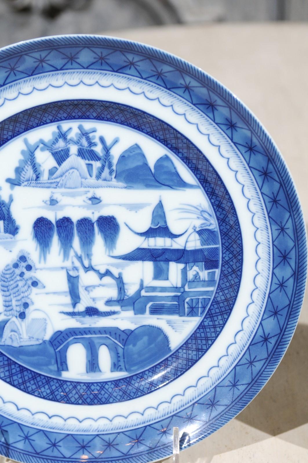 A set of two American Mottahedeh Blue Canton China plates with landscape scenes and latticed border, produced in Portugal. Presenting a charming blue and white decor featuring lovely Chinoiserie landscapes and architectures, each of these two plates
