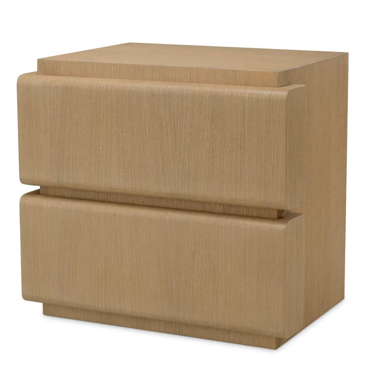 This nightstand in natural oak veneer brings warm, organic tones and refined simplicity to any bedroom. Designed with a distinctive drawer that extends slightly beyond the frame, the nightstand offers a sculptural look while maintaining clean,