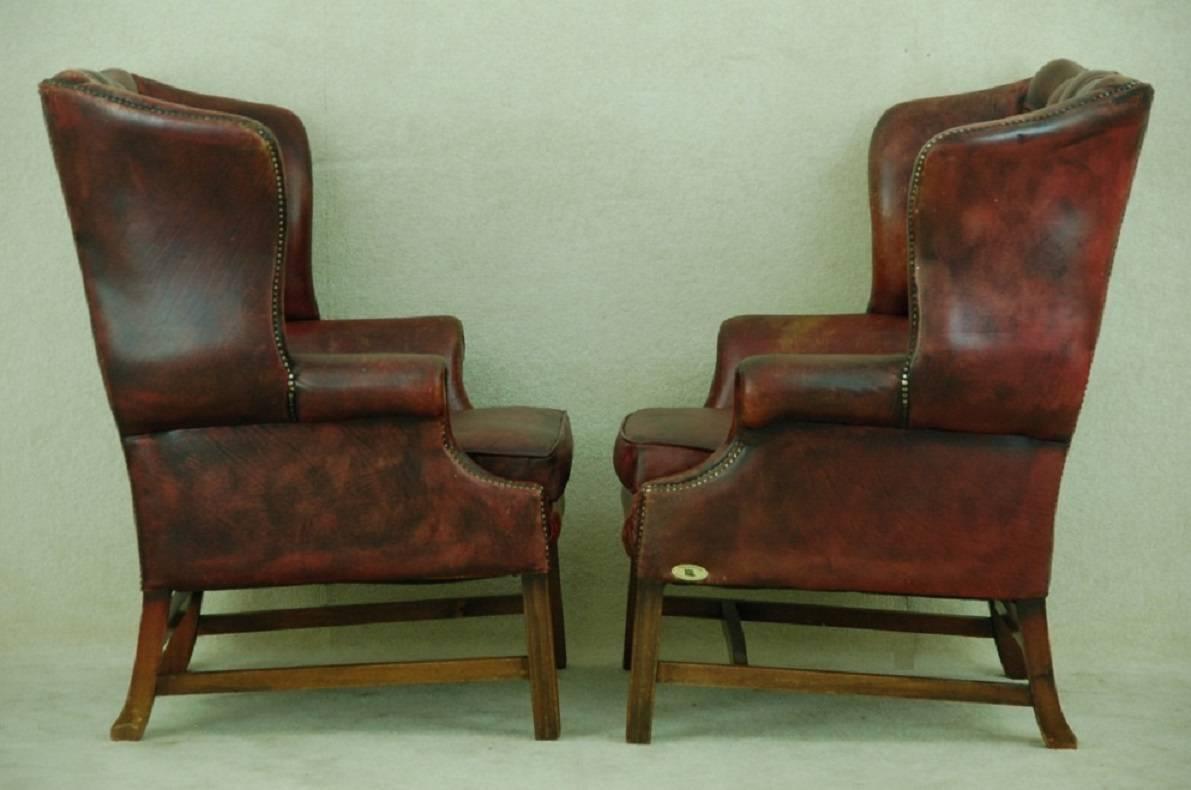 Rare find:
Early 20th century set of two identical Chesterfield high back chairs in leather natural hand dye oxblood red. 

Completely authentic, meaning small cracks (craquelé) in the leather but to remain this lovely old vintage look not