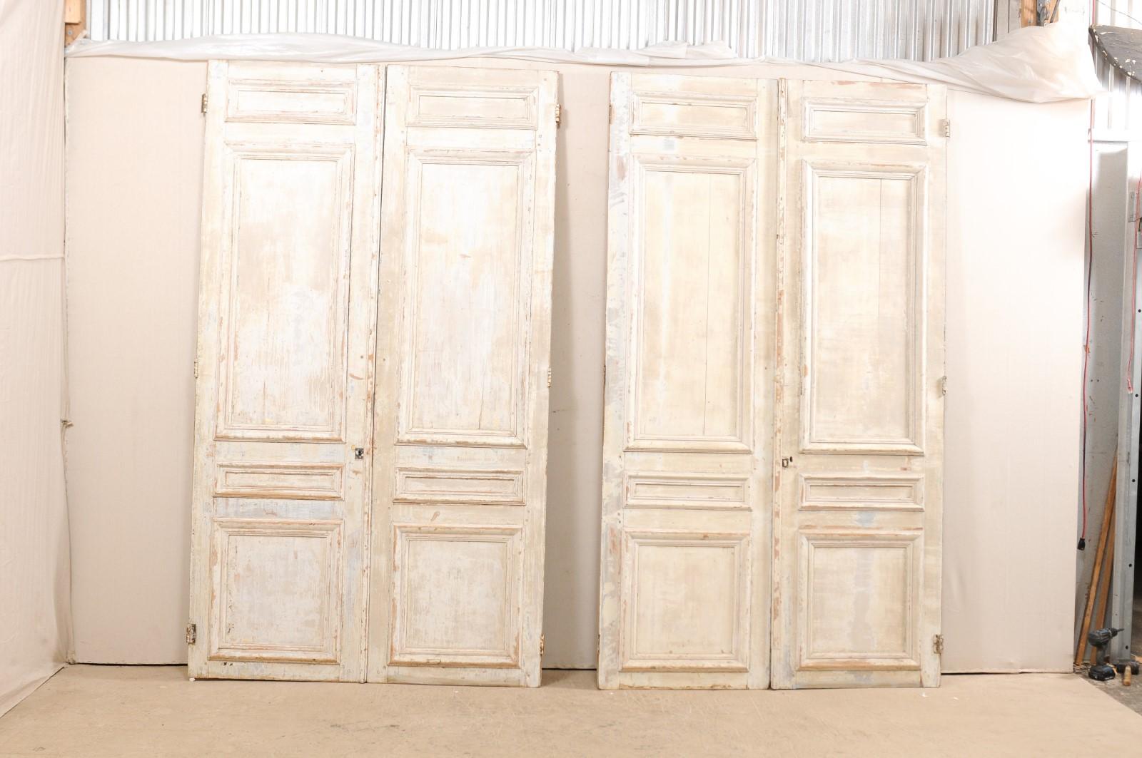 A set of two pairs of French panel doors from the mid-19th century. This set of 2 pair of French doors each feature four nicely molded panels at front, with more plain, recessed panels on their backsides, standing approximately 8.75 feet in height.