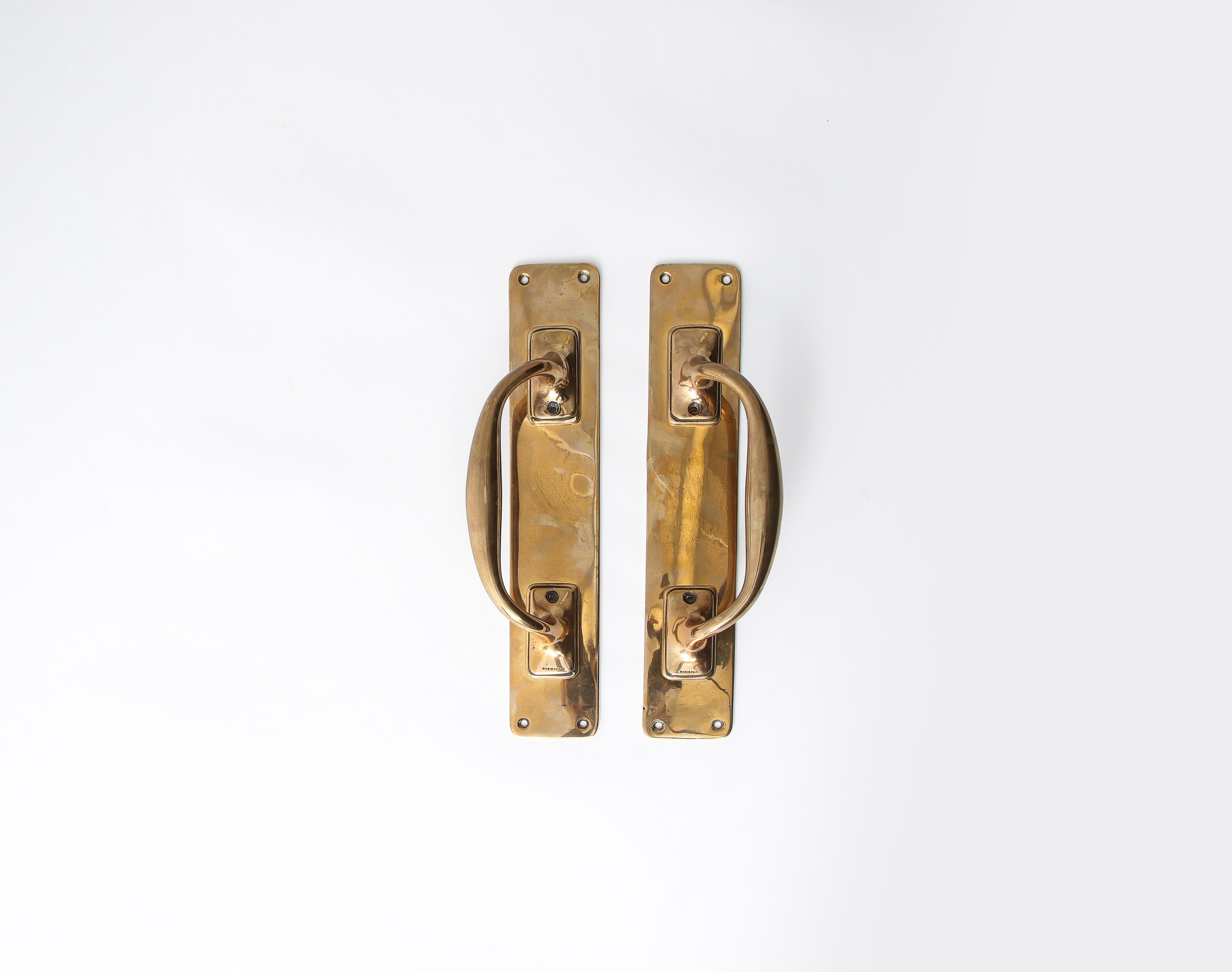 Set of two polished bronze vintage door handles on larger rectangular plaques. Lovely well-worn patina. The handles are each fitted with four holes in each of the corners for nails.