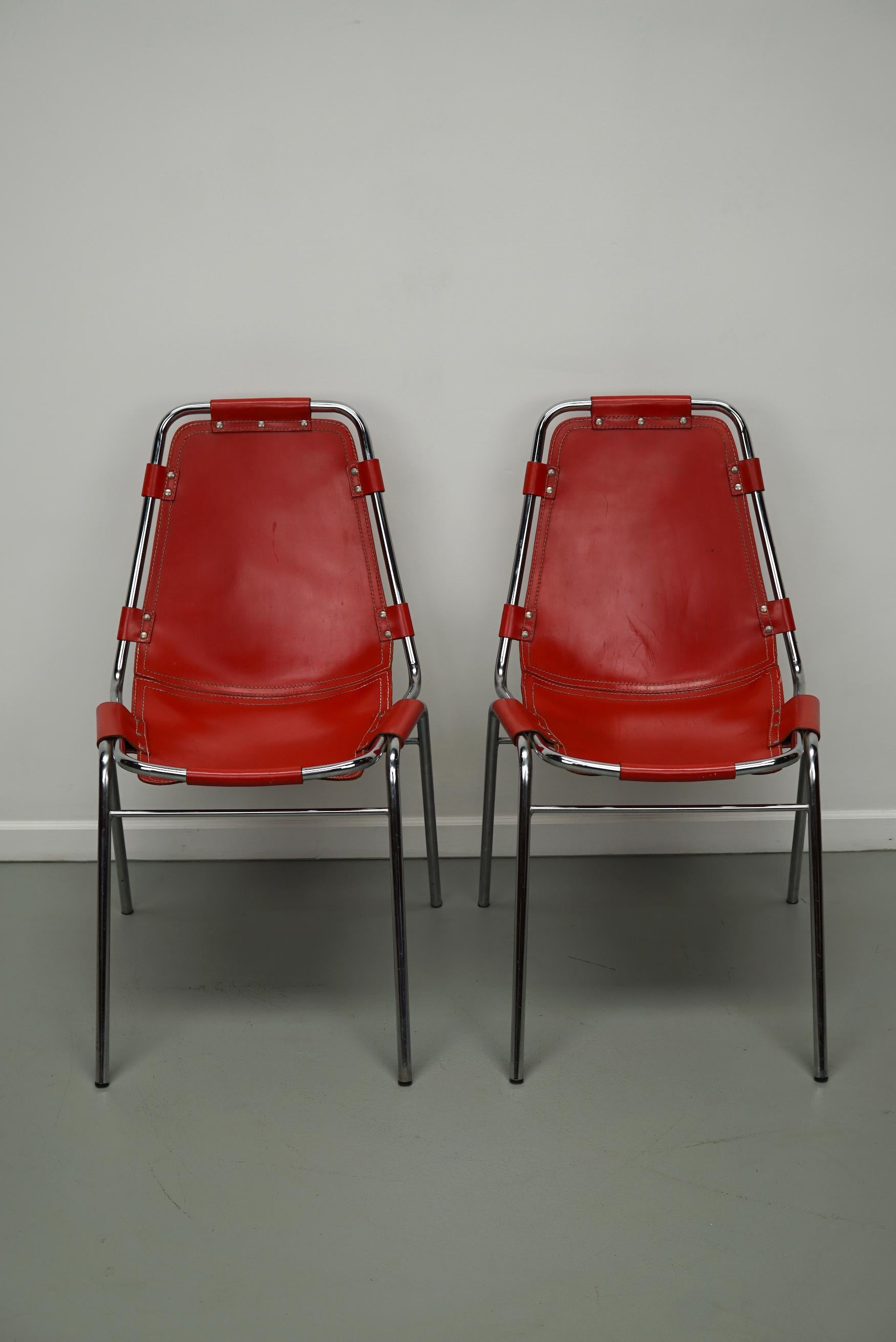 Diese Stühle wurden in den 1960er Jahren von Charlotte Perriand für Les Arcs entworfen. Sie haben einen verchromten Rohrrahmen und dicke rote Ledersitze. Die Ledersitze sind in einem sehr guten Vintage-Zustand mit nur einer zusätzlichen Niete für