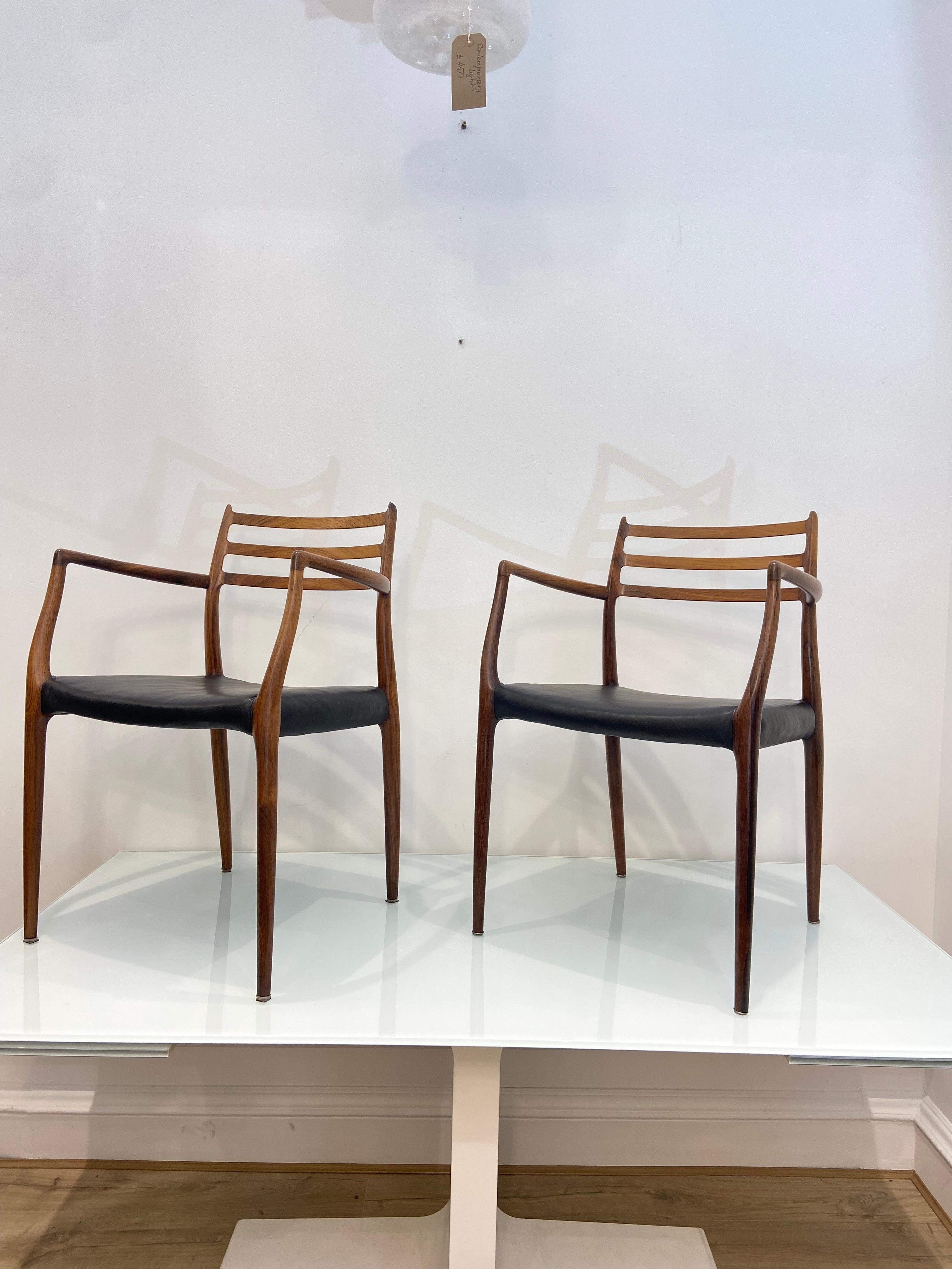 Set Of Two Rosewood Niels Otto Moller Model 62 Dining Chairs With Arms In Black Leather.

This set of two Mid 20th Century Niels Otto Møller dining chairs are a true rare find for mid-century design enthusiasts. Crafted from rich, exotic rosewood