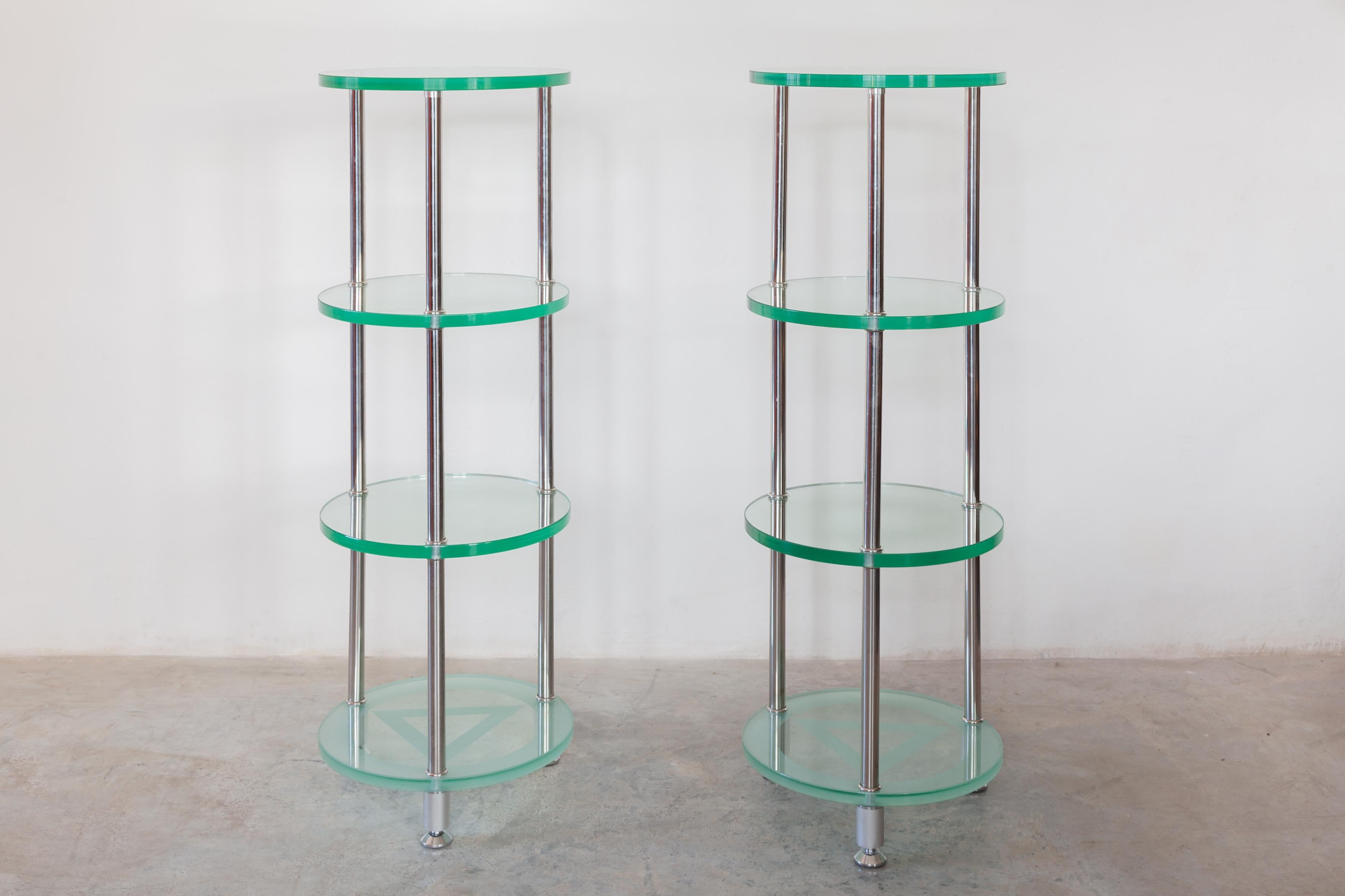 Set of two round glass and chrome console or display of decorative objects. The consoles consist of four thick round faceted glass shelves, the bottom shelf is etched solid connected with a metal chromed frame the legs can be adjusted from below for