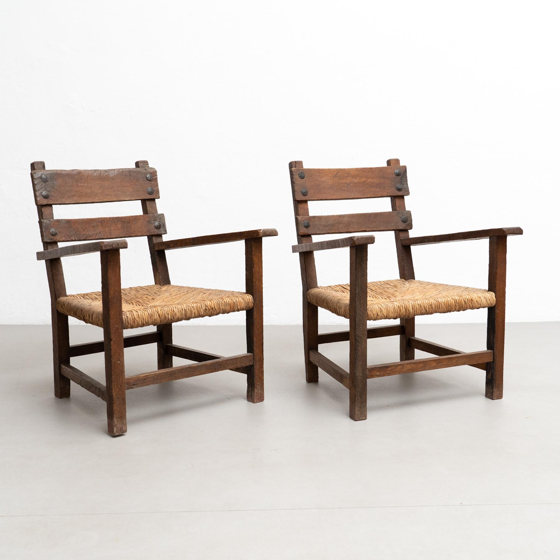 Elevate your living space with this charming set of two rustic armchairs, harkening back to the early 20th century. Crafted with meticulous care, these armchairs showcase a timeless design that seamlessly blends solid wood and rattan.

The sturdy