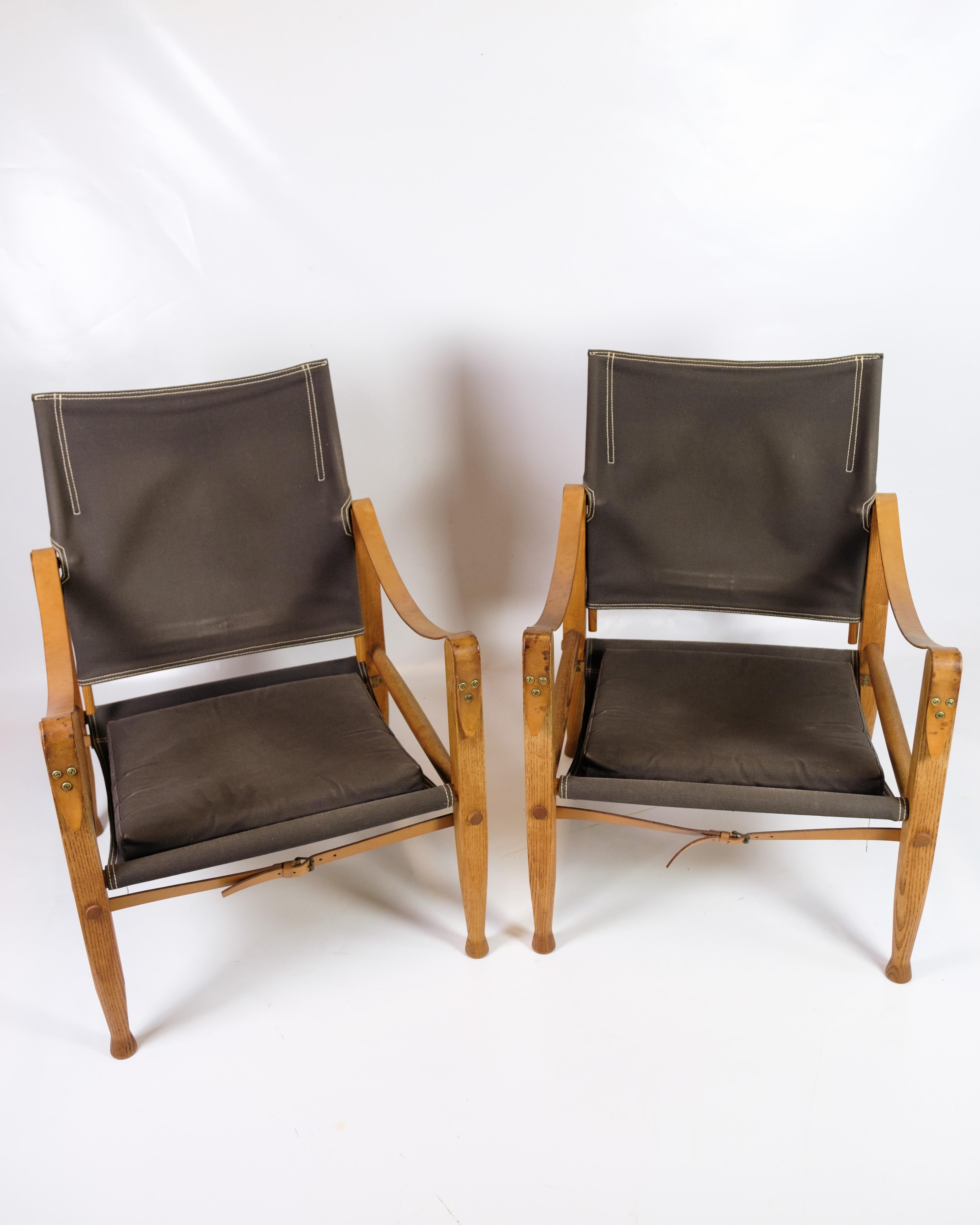 A set of safari armchairs designed by Kaare Klint and manufactured by Rud. Rasmussen. The chairs are made of ash wood with a seat and back in brown canvas and armrests in full grain leather. The Safari chairs are known for their simple and
