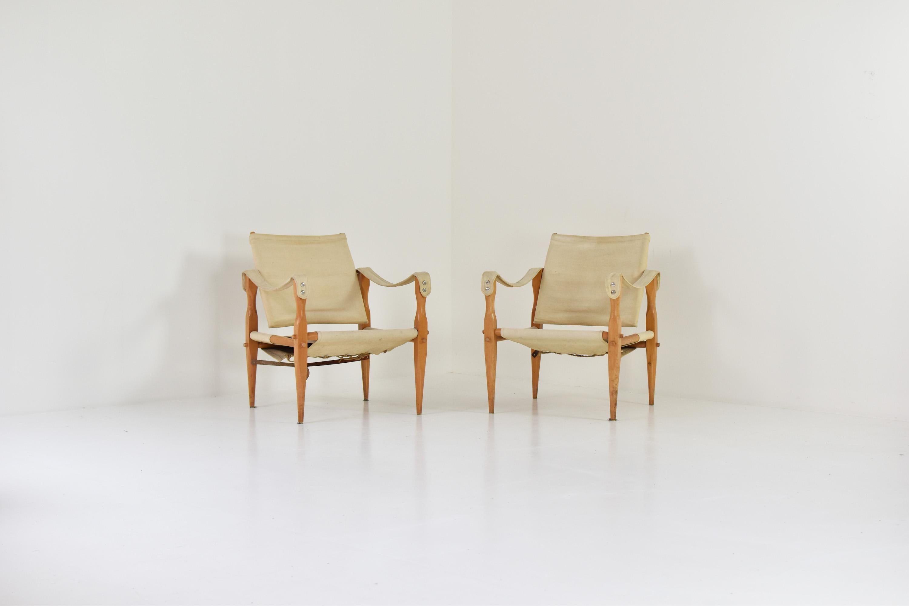 Set of two ‘Safari’ lounge chairs from Denmark, produced in the 1960’s. This set features a frame made out of ash and seats made out of cotton. Age related marks as seen on the pictures. From one chair the leather strap is missing. In the manner of