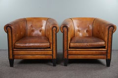 Set of two sheepskin club chairs with button-tufted armrests.