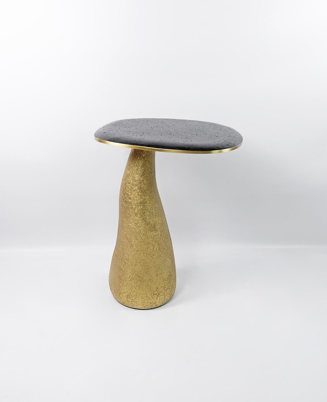 This set of 2 tables is made of lava stone marquetry top with brass trims.
The base is made of wood with a gilded semi-raw glass fiber inlaying.
The semi raw finishing brings an interesting texture thanks to the nice organic shape of the