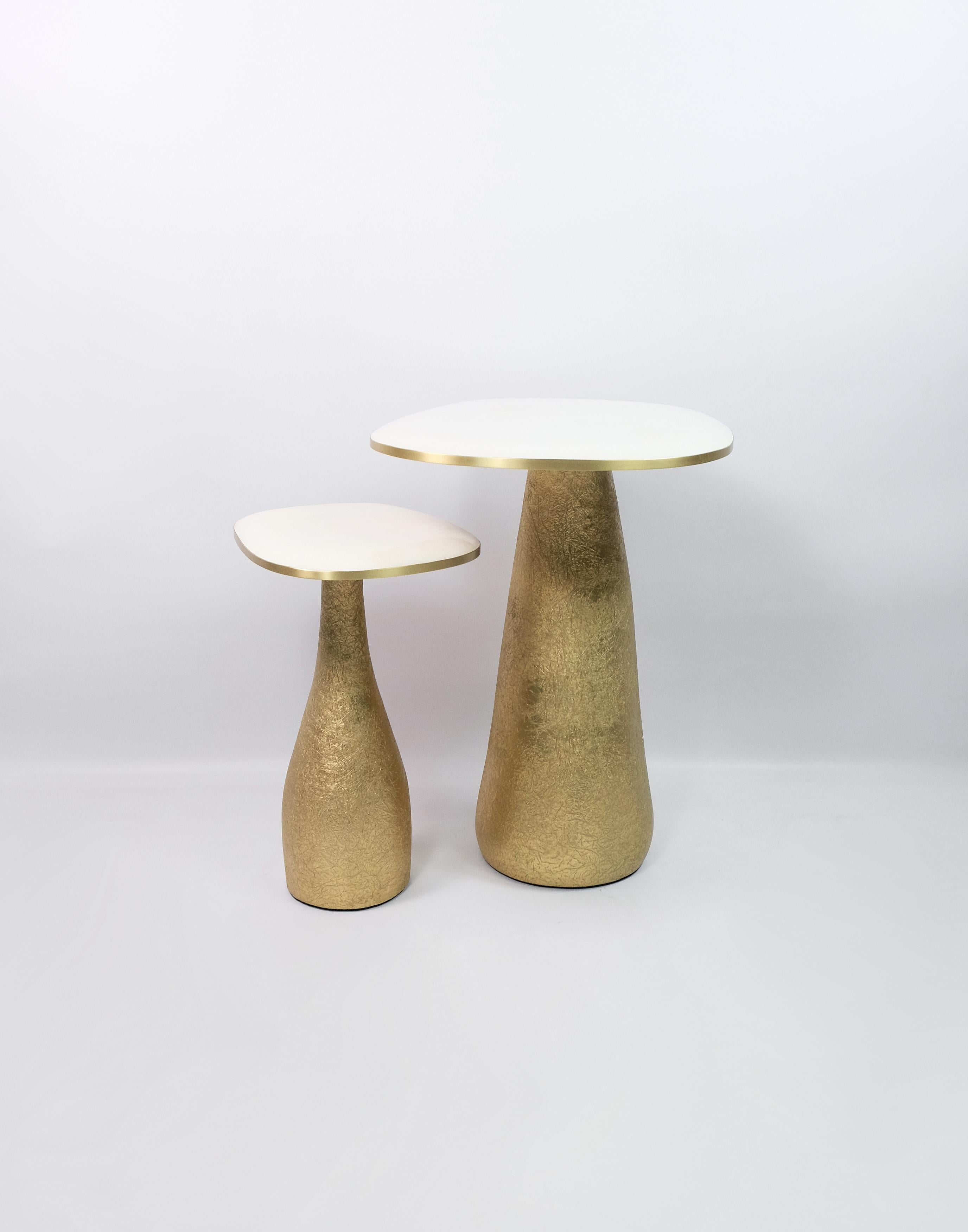 This set of 2 tables is made of a white rock crystal marquetry top with brass trims.
The base is made of wood with a gilded semi-raw glass fiber inlaying.
The semi raw finishing brings an interesting texture thanks to the nice organic shape of the