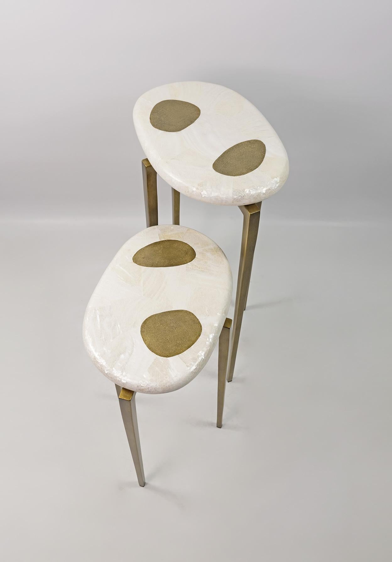 Ces jolies tables d'appoint sont réalisées en marqueterie blanche polie avec un décor en laiton texturé.

Le plateau est de forme ovale organique et les pieds en métal ont une patine laiton antique.

Les tables sont petites et très polyvalentes.