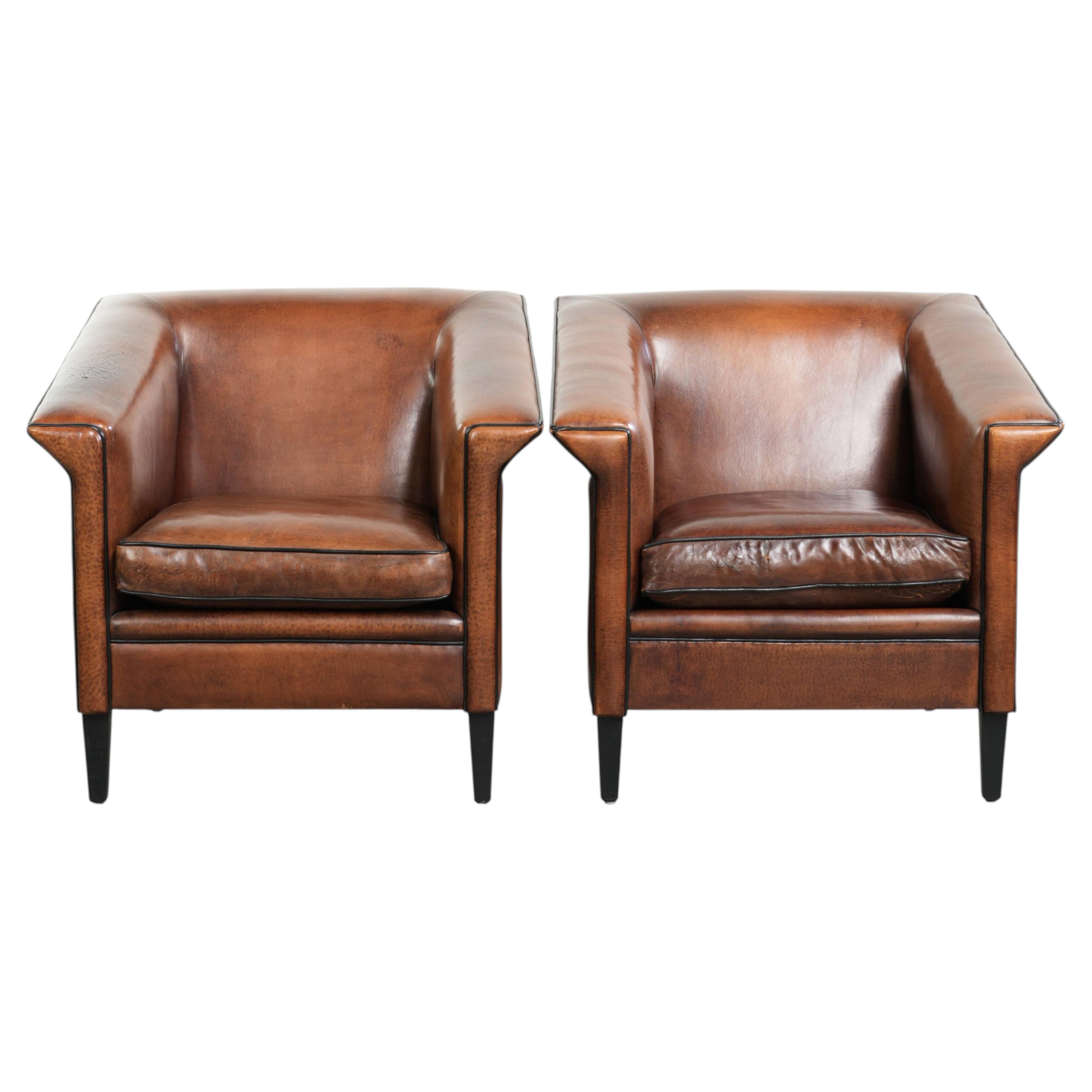 Set of two sleek sheepskin Art Deco design armchairs with black piping