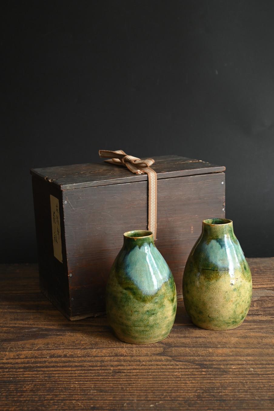 Se trata de un par de pequeños jarrones florales de cerámica Mino, que se cree que fueron fabricados a finales del periodo Edo, concretamente en el primer año de la era Bunka (1804). En el interior de la tapa de la caja de madera hay inscripciones