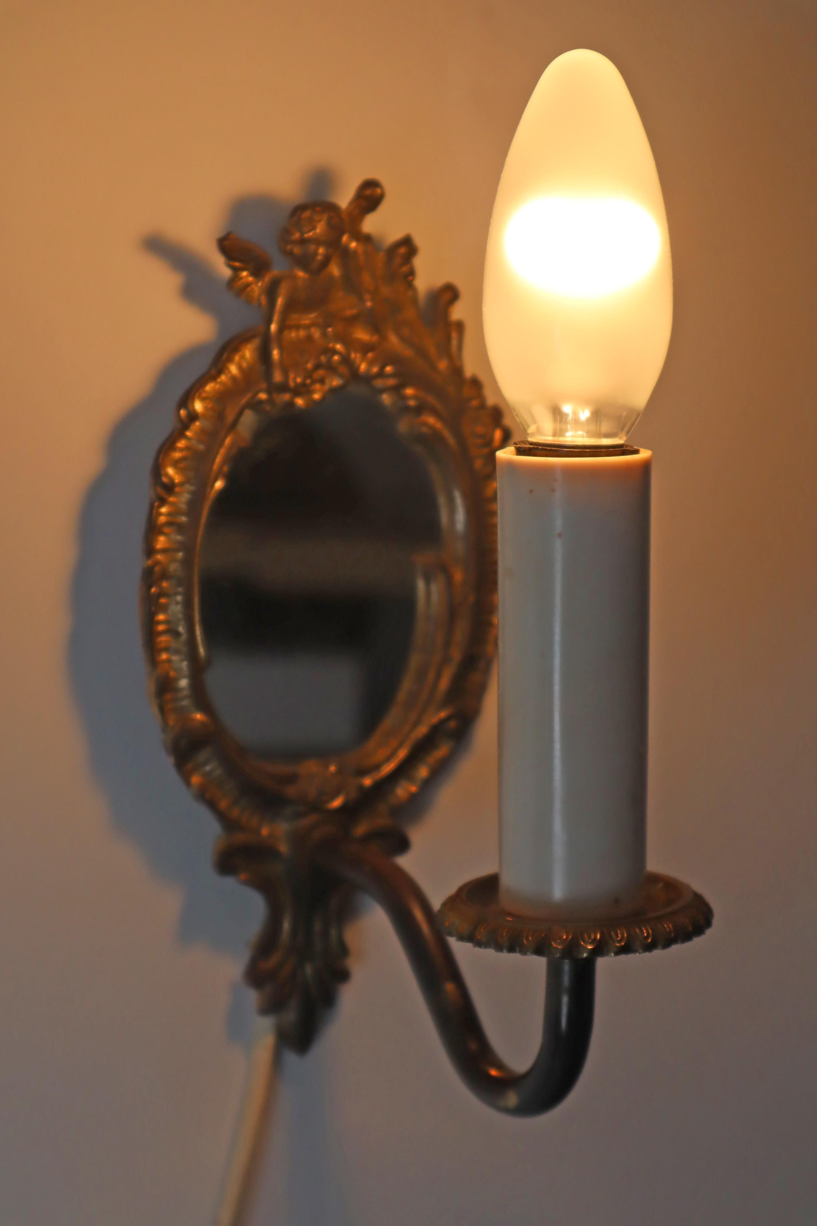 Si tratta di un set di due lampade da parete, ciascuna con un angelo sulla parte superiore. Entrambe le lampade sono dotate di specchietti. Le lampade sono placcate in oro. La forma rende queste lampade ancora più belle. Uno specchio è mezzo