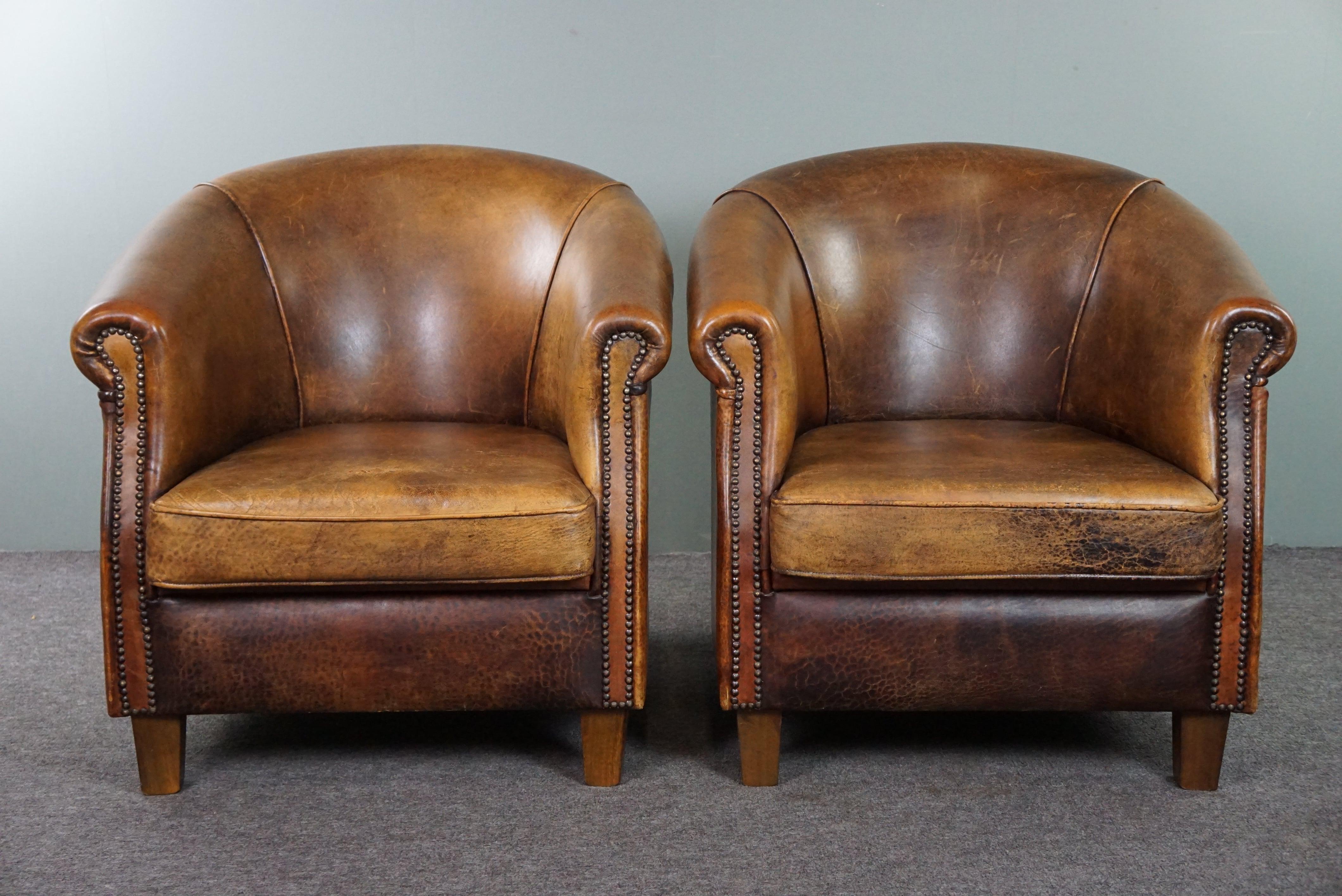Offered is this cool set of two sturdy sheep leather club chairs in a beautiful dark cognac color and finished with nails.

This wonderful set of sturdy sheep leather armchairs with experience have already had a life behind them but are also looking