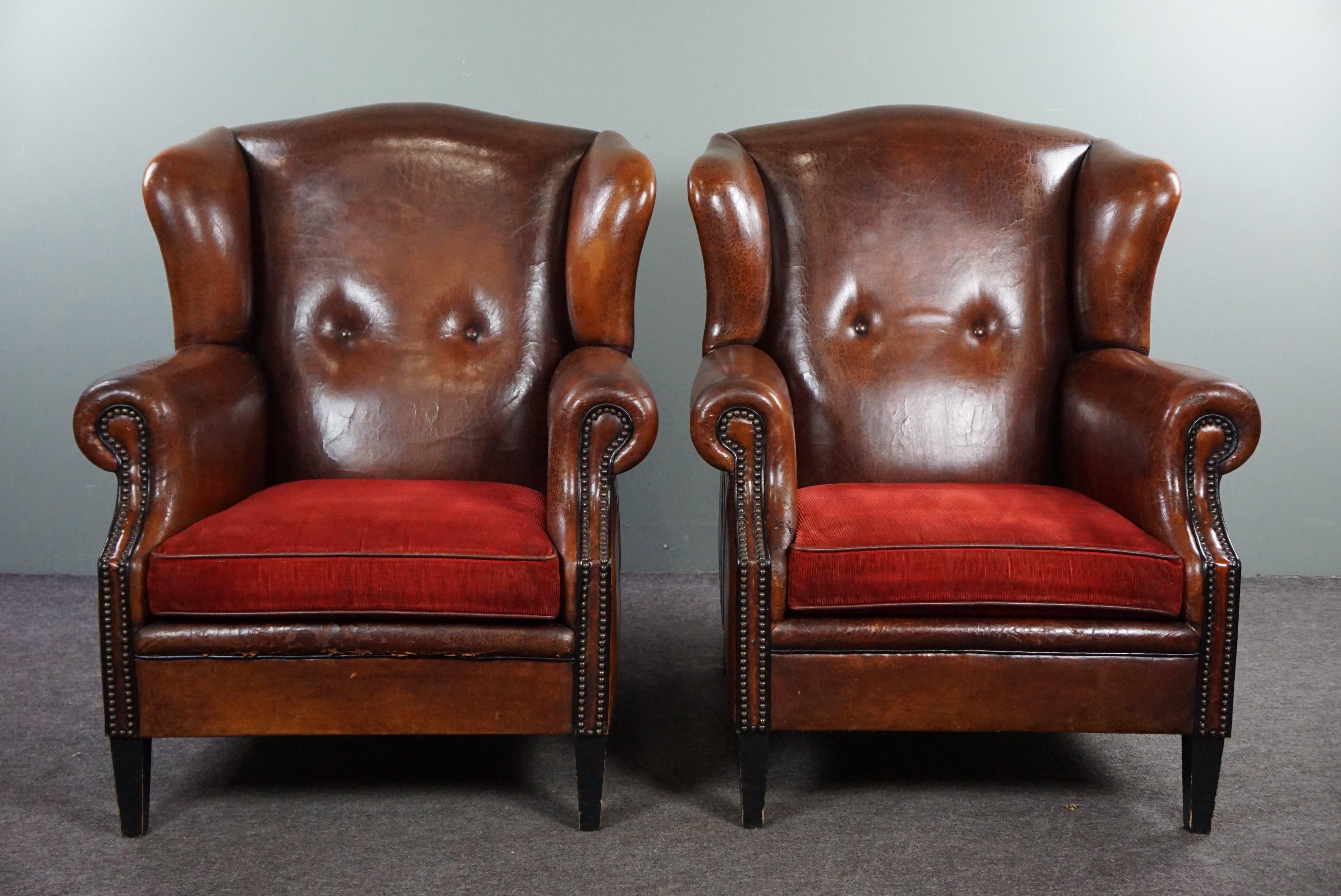 Offered are these sheep leather wing chairs with seat cushions in a beautiful red color.

Imagine yourself in an English country house with these chic wing chairs.
The first thing you notice about these beautiful wing chairs are of course the seat