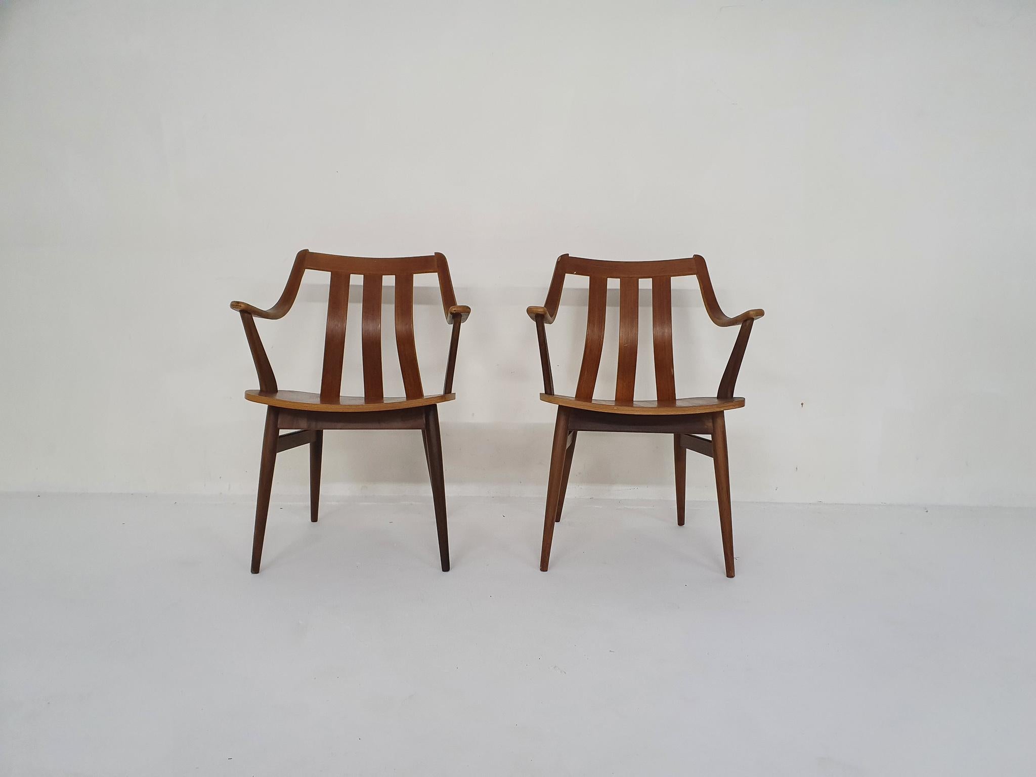 Teak dining chairs with arm rests.